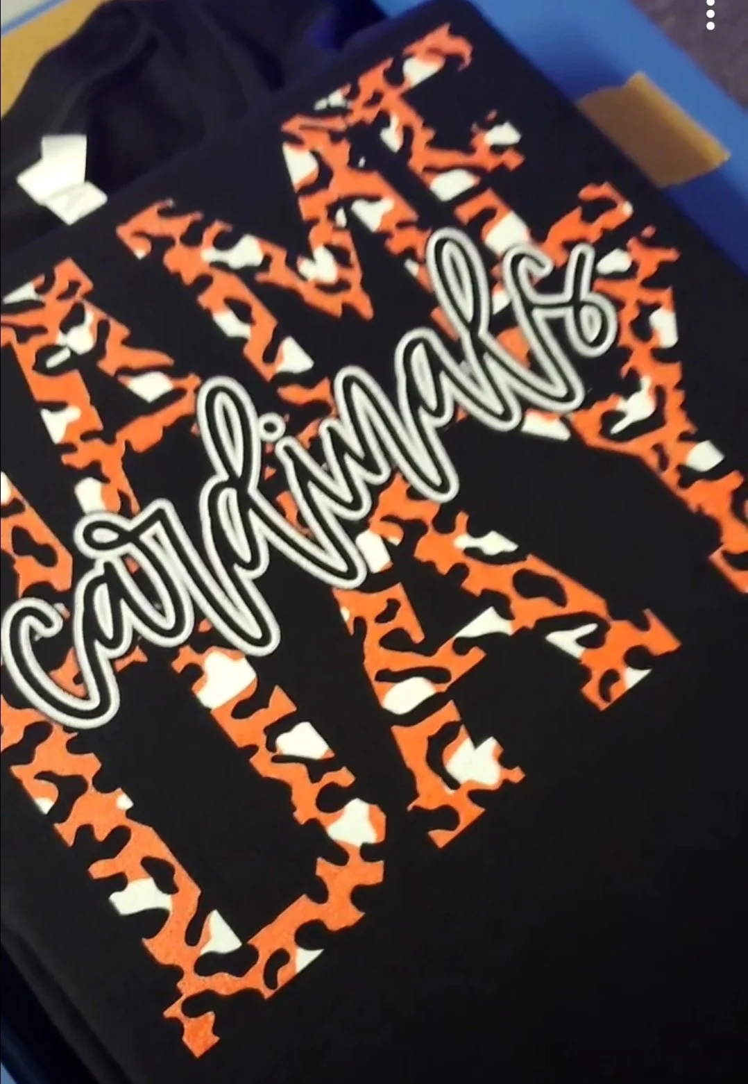 A black t-shirt with orange and white cheetah print patterns and the words "Game Day" written across the front in white cursive font.