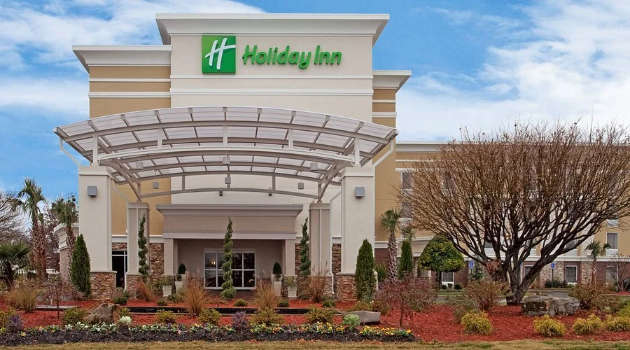 Holiday Inn hotel entrance with landscaped garden and modern architecture.