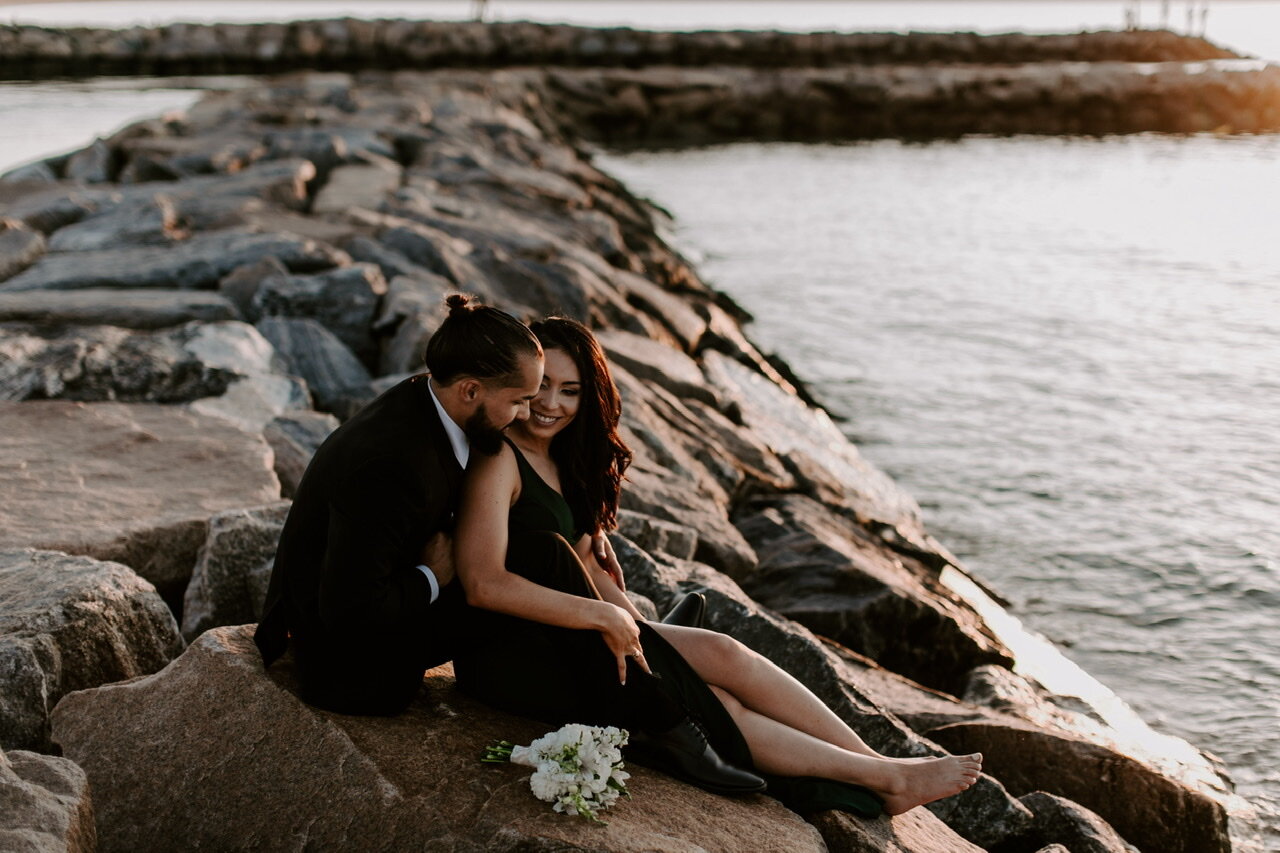 Couple sitting along rocks on water