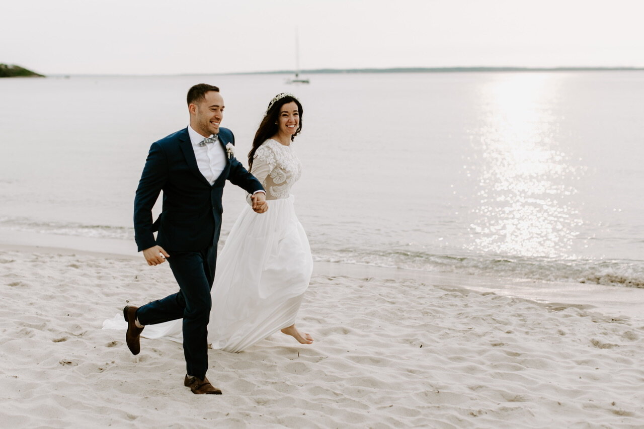 A couple running down the beach hand in hand