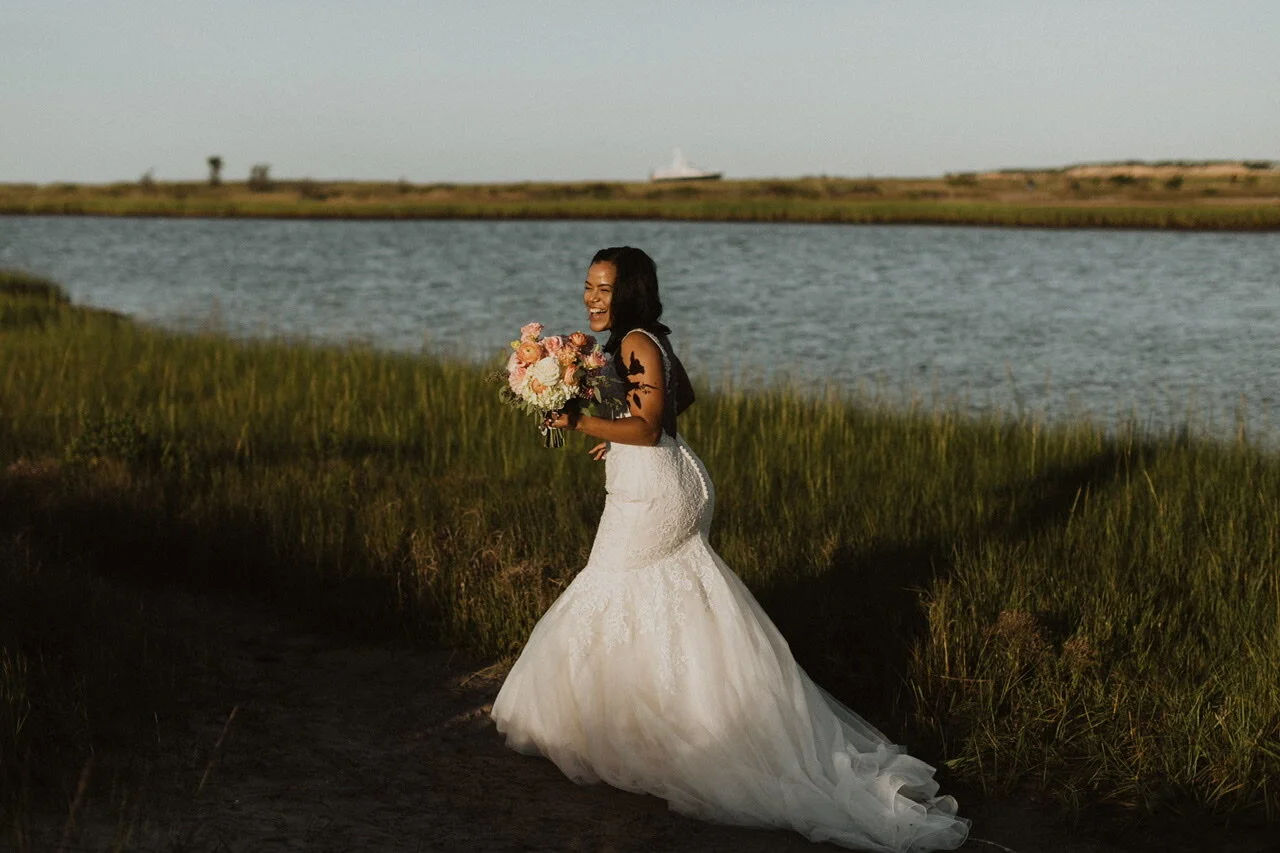 Bride walking through beach grass with pink and white bouquet