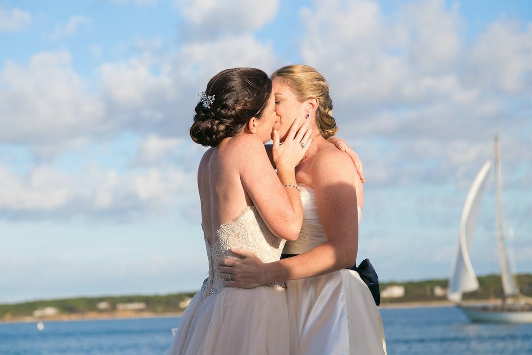 Couple kissing on Marthas Vineyard with ocean and sailboat in the background.jpg