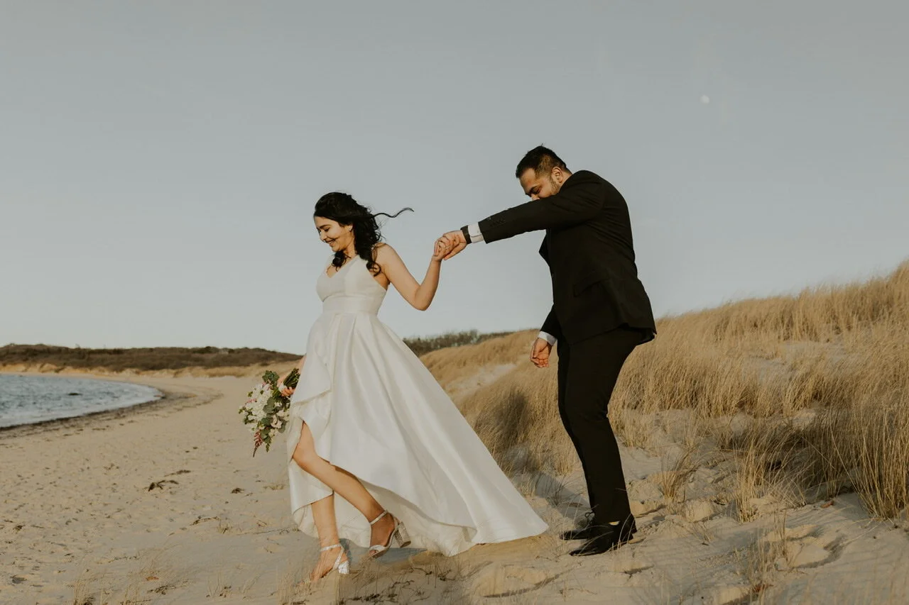 Bride leading groom on to the beach