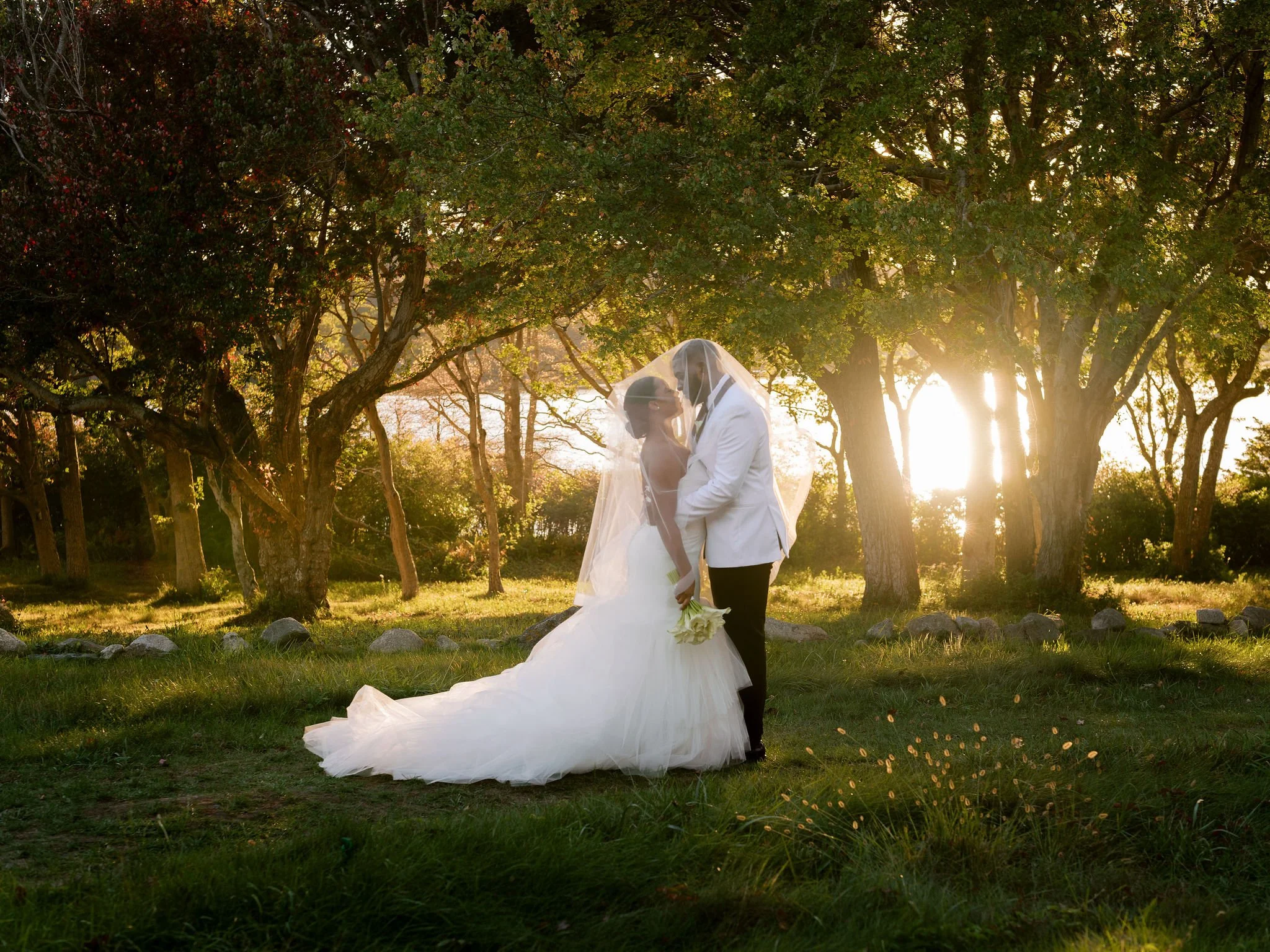 Bride & Groom with sun reflecting on lake behind trees