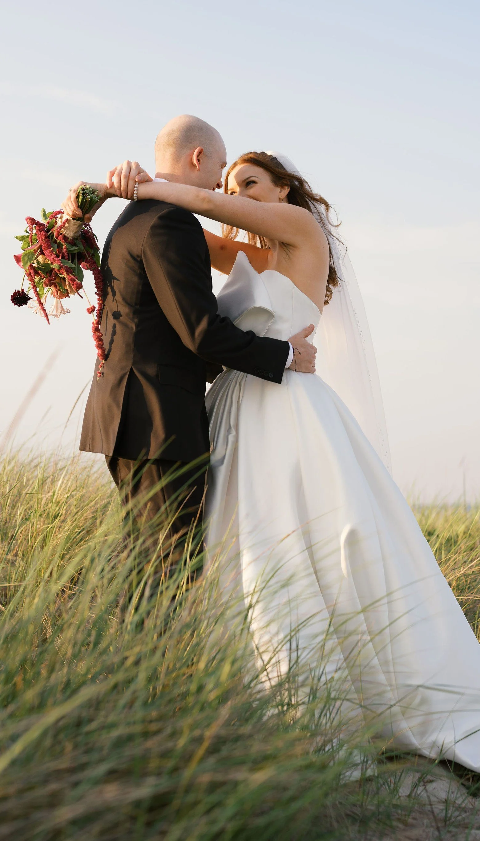 Bride & Groom dancing in tall beach grass with dramatic bouquet