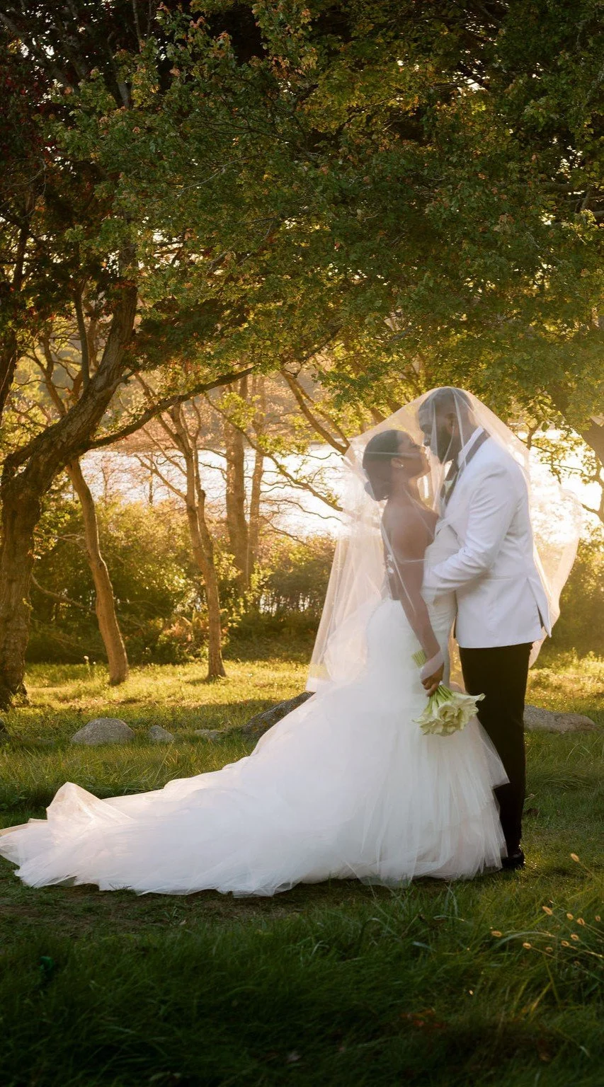 Bride & Groom in meadow under veil with autumn leaves and water in background