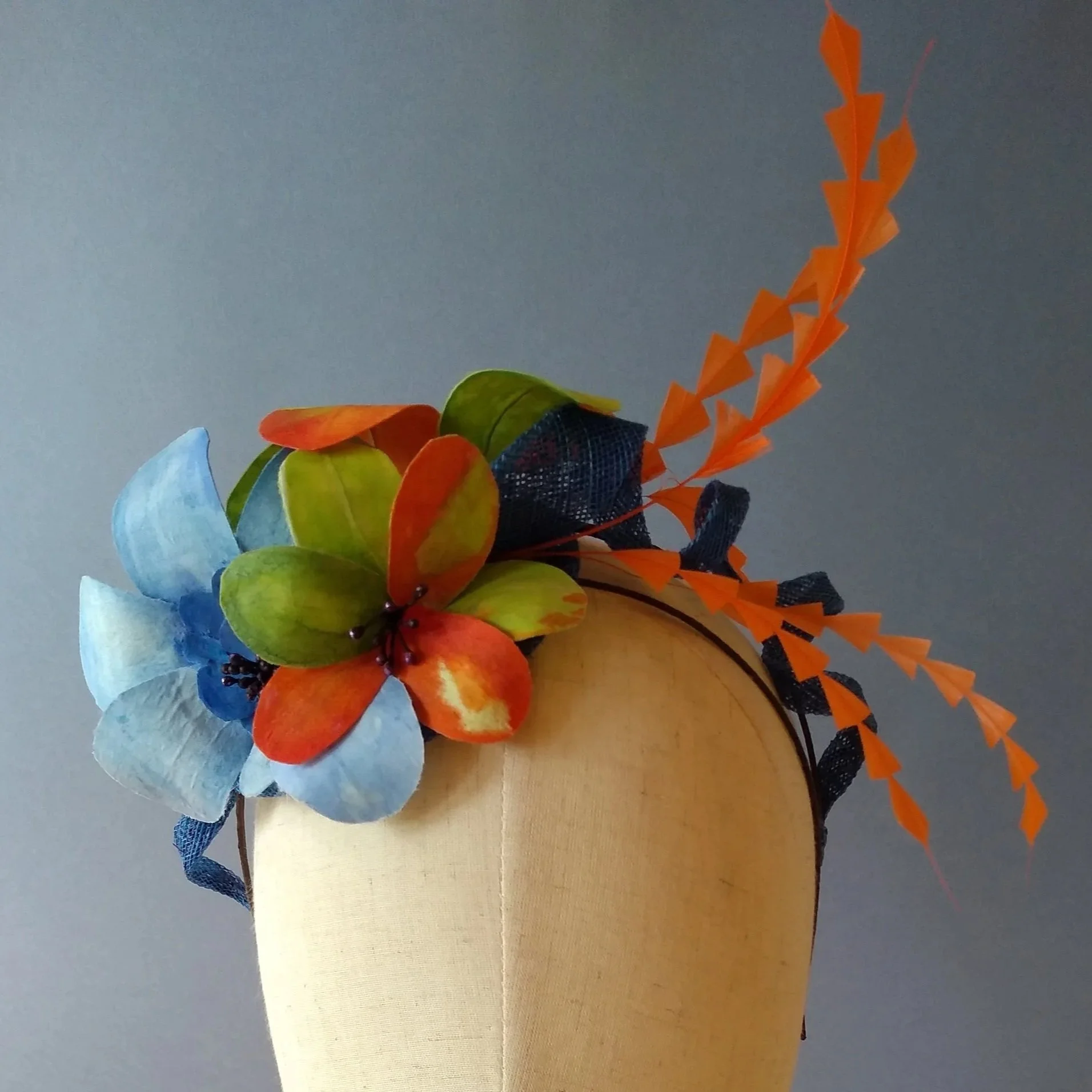 Small hat on a bespoke headband with handmade fabric flowers and decorative feathers.