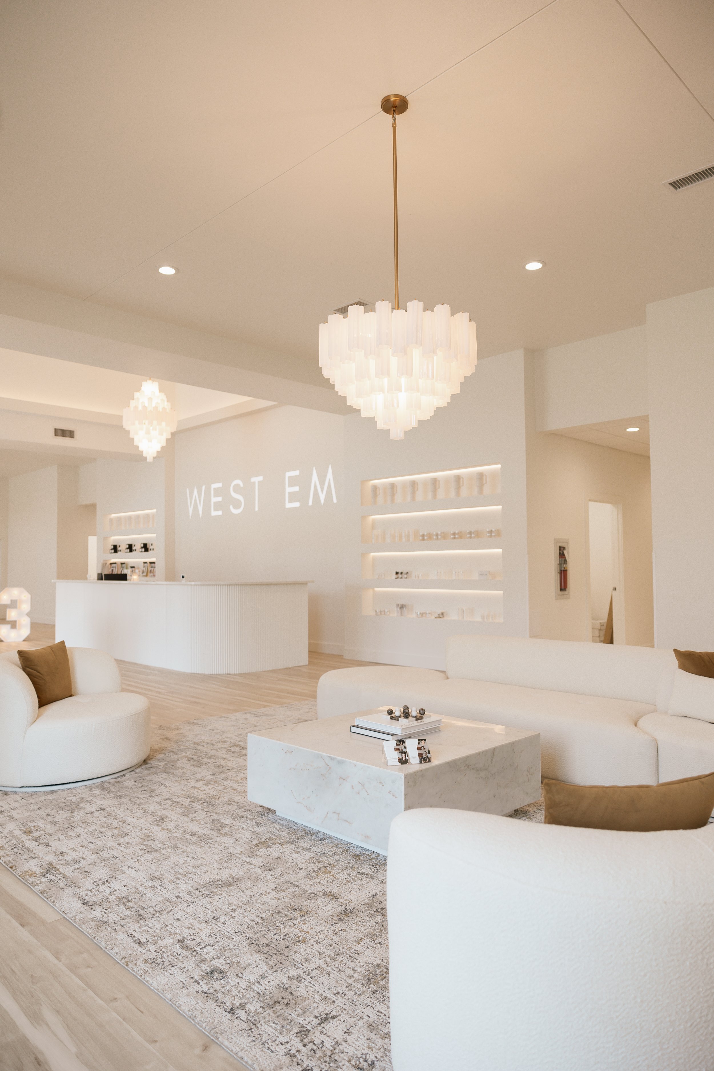 West Em Medical Spa lobby with white and gold accents and West Em skincare products in the background