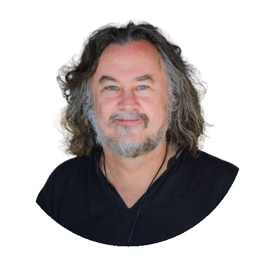 A man with shoulder-length curly hair, a beard, and a mustache, wearing a black shirt, smiling at the camera.