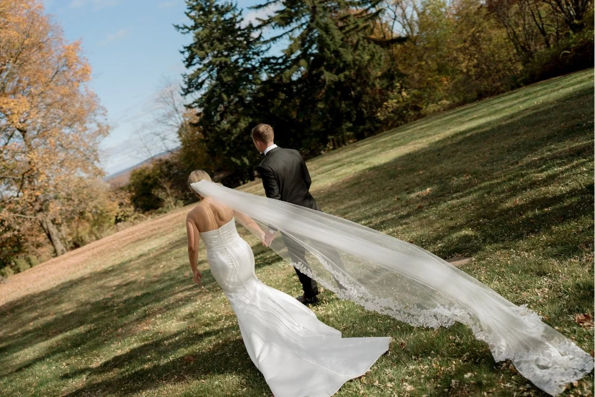 The bride and groom walk away, white dress billowing in the wind.