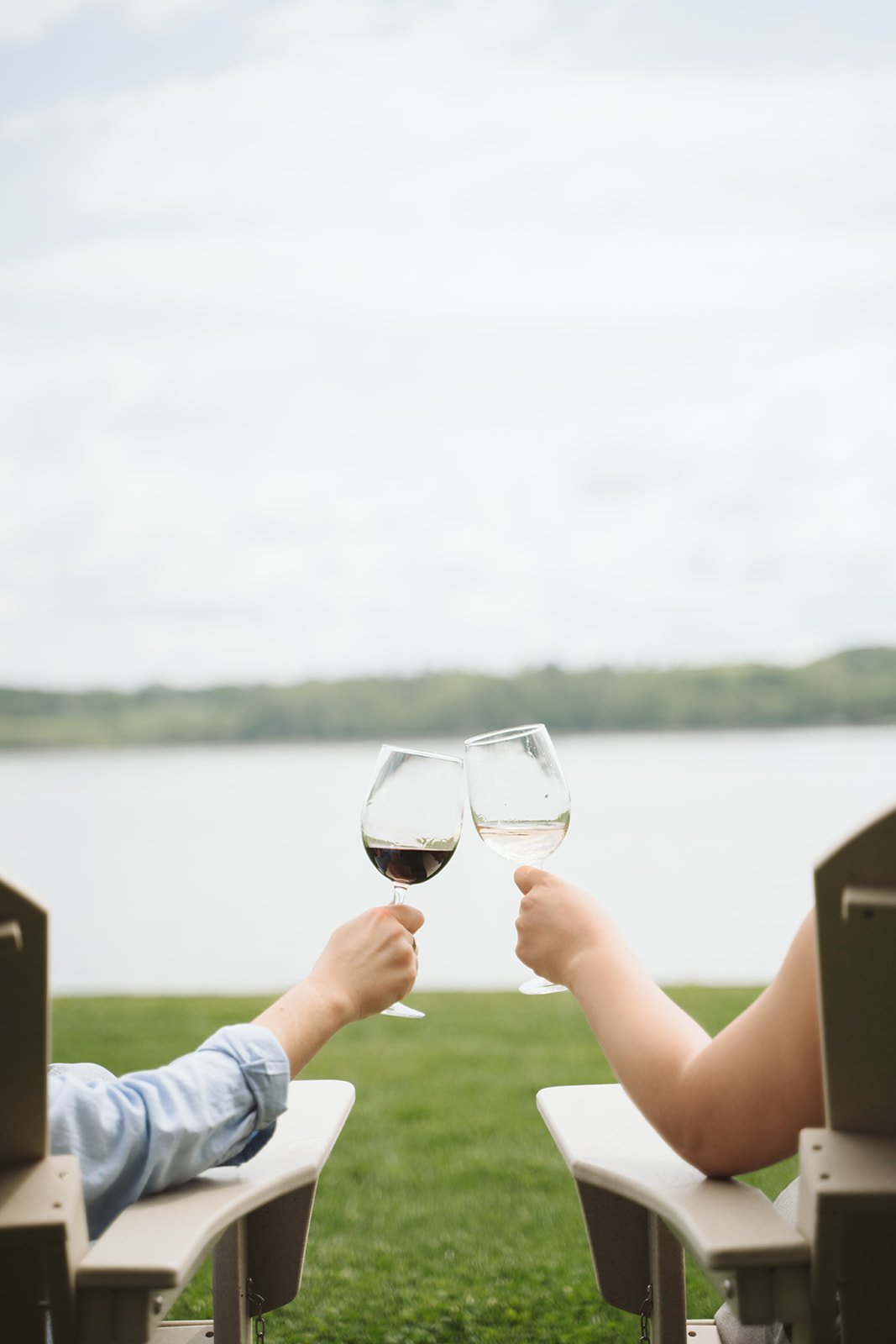 Adirondack chairs on the open lawn, steps from the water's edge.