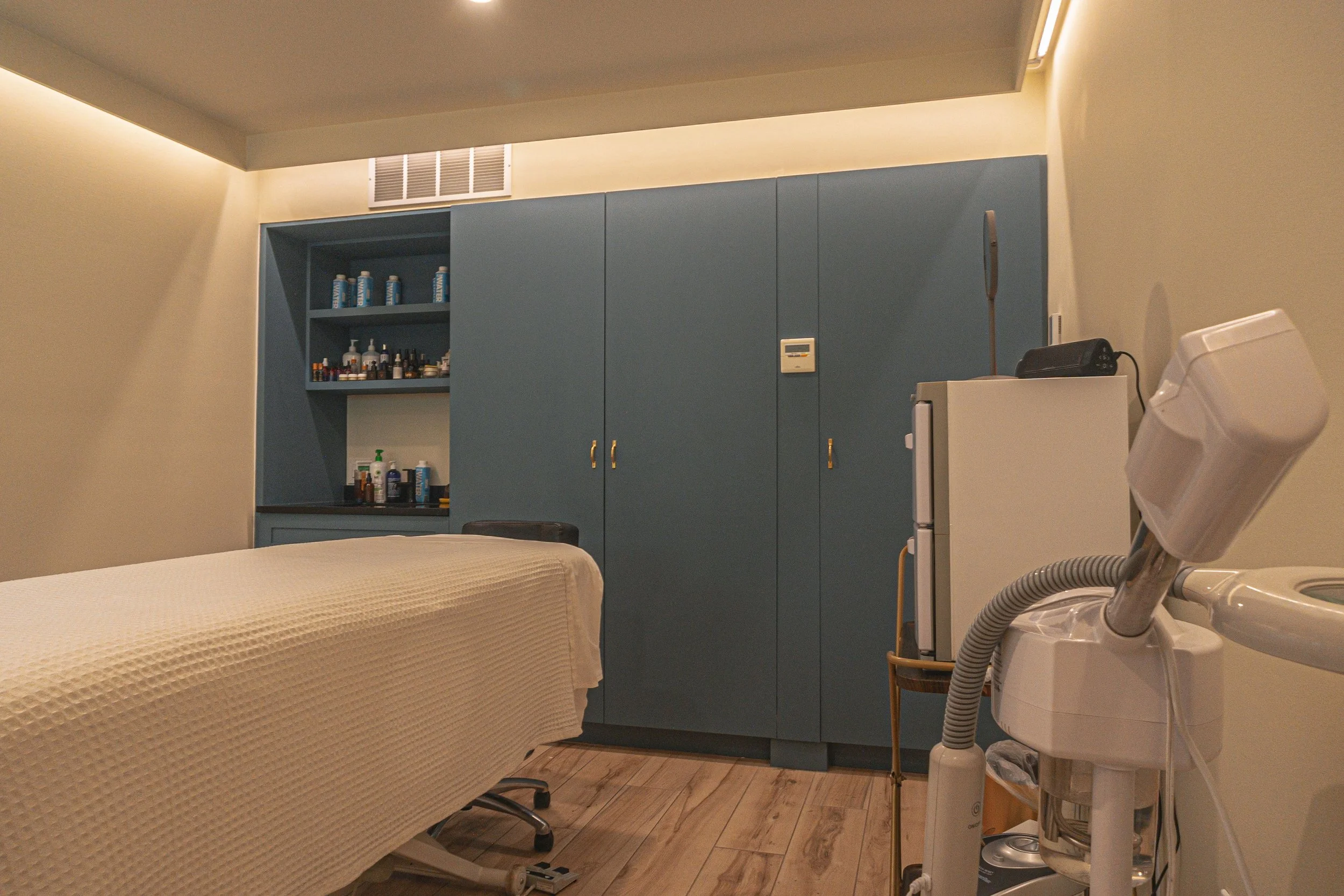 Treatment room with a massage bed and cabinets filled with products