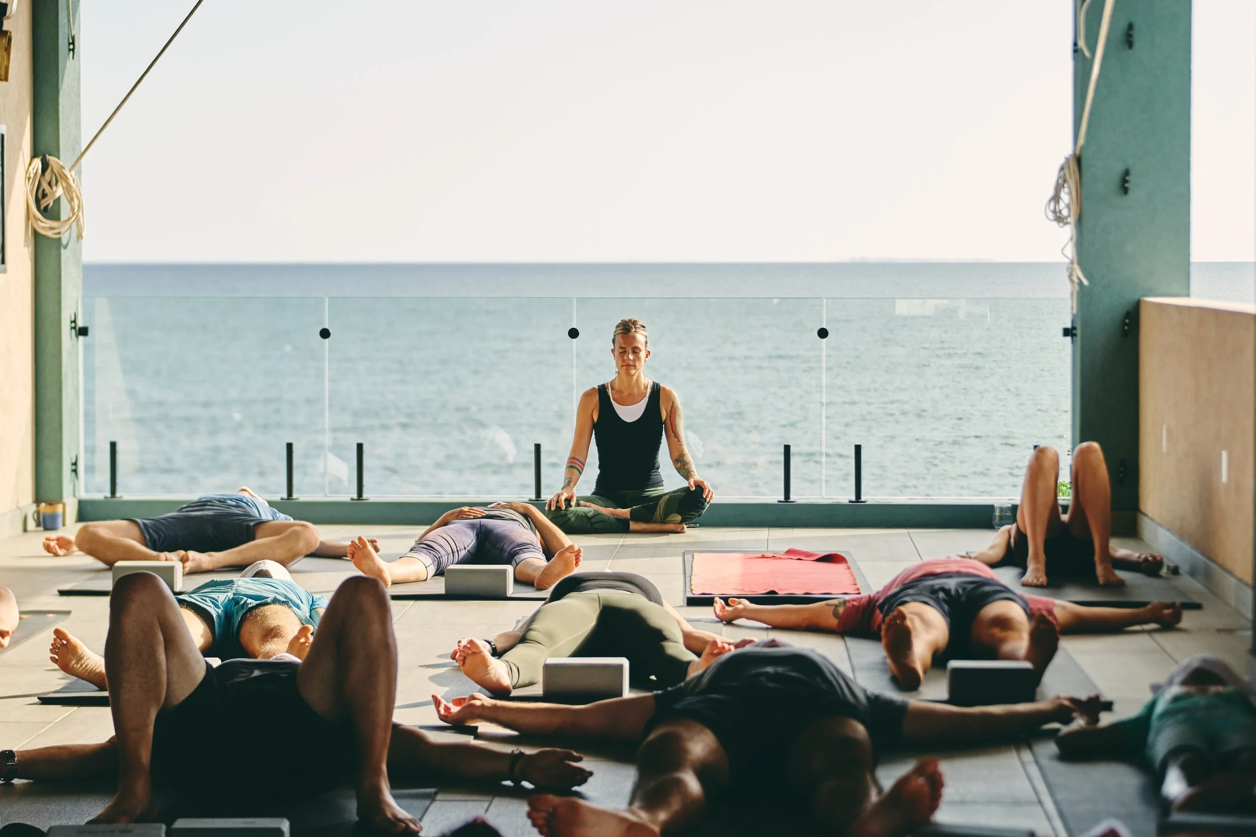 Yoga teacher leading a seated meditation on an open-air deck overlooking the Caribbean Sea