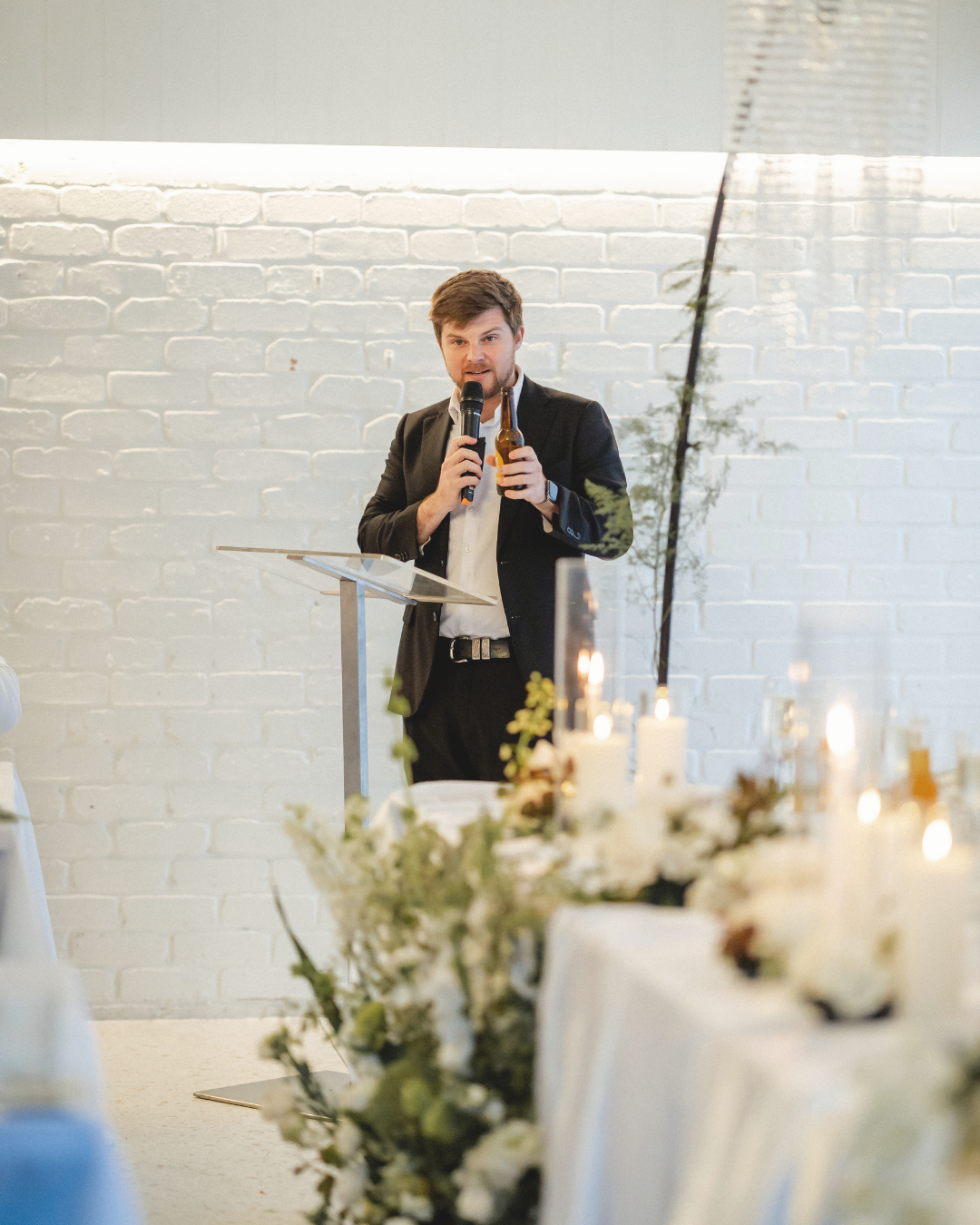 Brisbane wedding MC Dylan Bond speaking into a microphone at a wedding reception