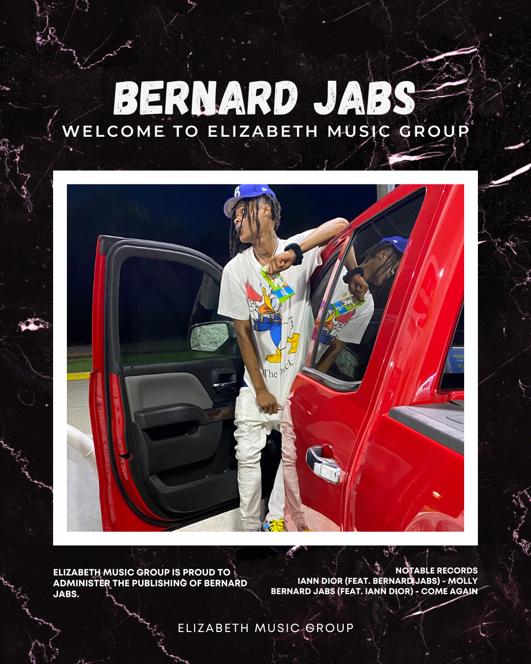 A young man with dreadlocks wearing a Disney Donald Duck T-shirt, white pants, and a blue cap leaning against the open door of a red vehicle at night.