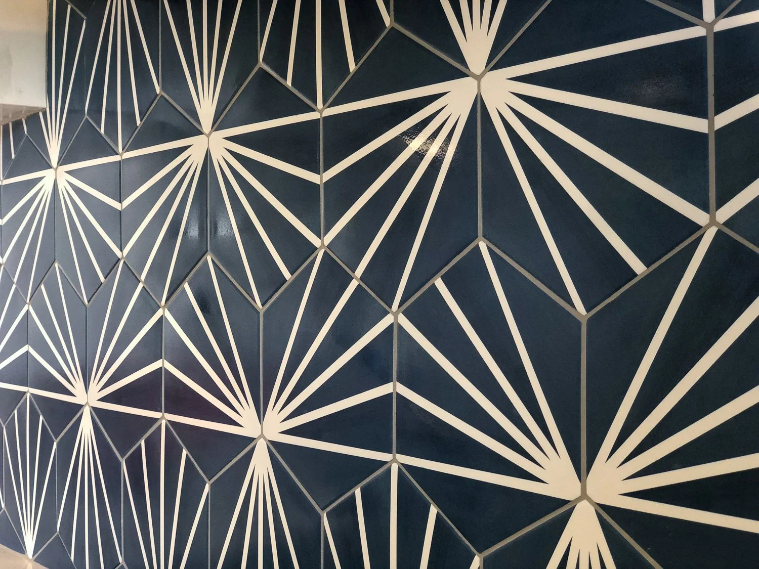 Geometric blue wall with white lines forming a pattern of interconnected triangles and polygons.