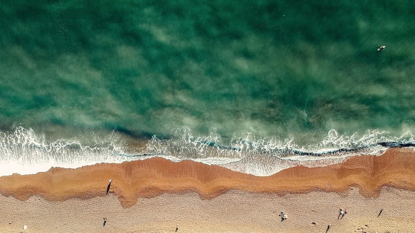 Aerial view of waves breaking on a beach.jpg