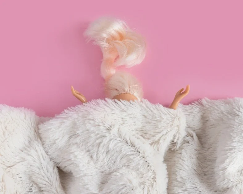 En nallebjörn med fluffigt vitt hår, sittande mot en rosa bakgrund, med armarna utsträckta.