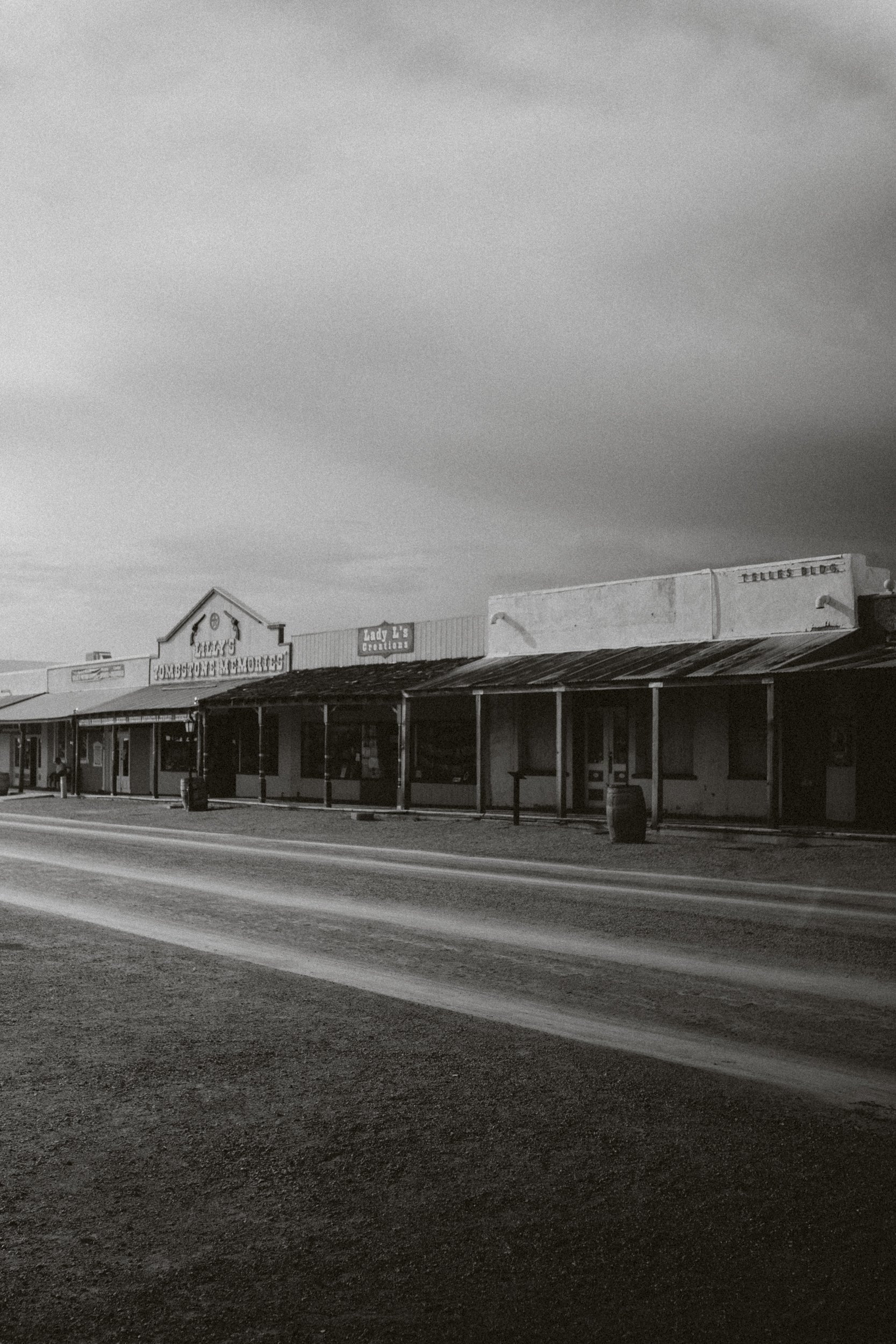 Une rue déserte avec des bâtiments de style western, enseignes telles que 'Tombstone Memory' et 'Lady E's Creations'.