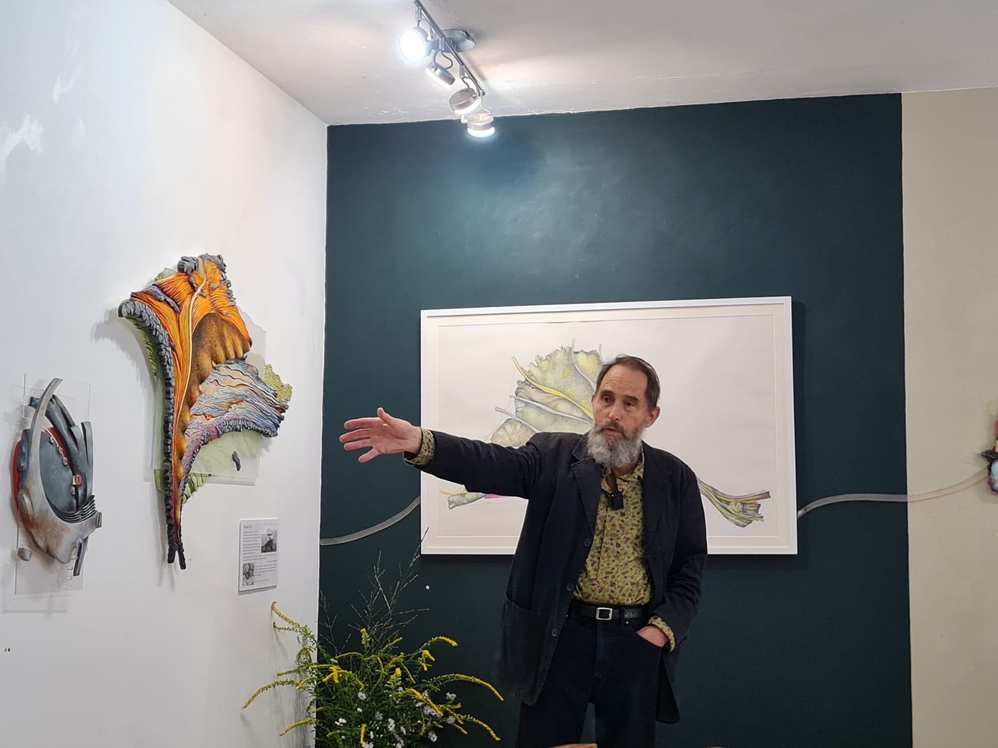 Pete Bousfield explaining green and blue sculptural artworks inspired by the landscape of Bodmin Moor.