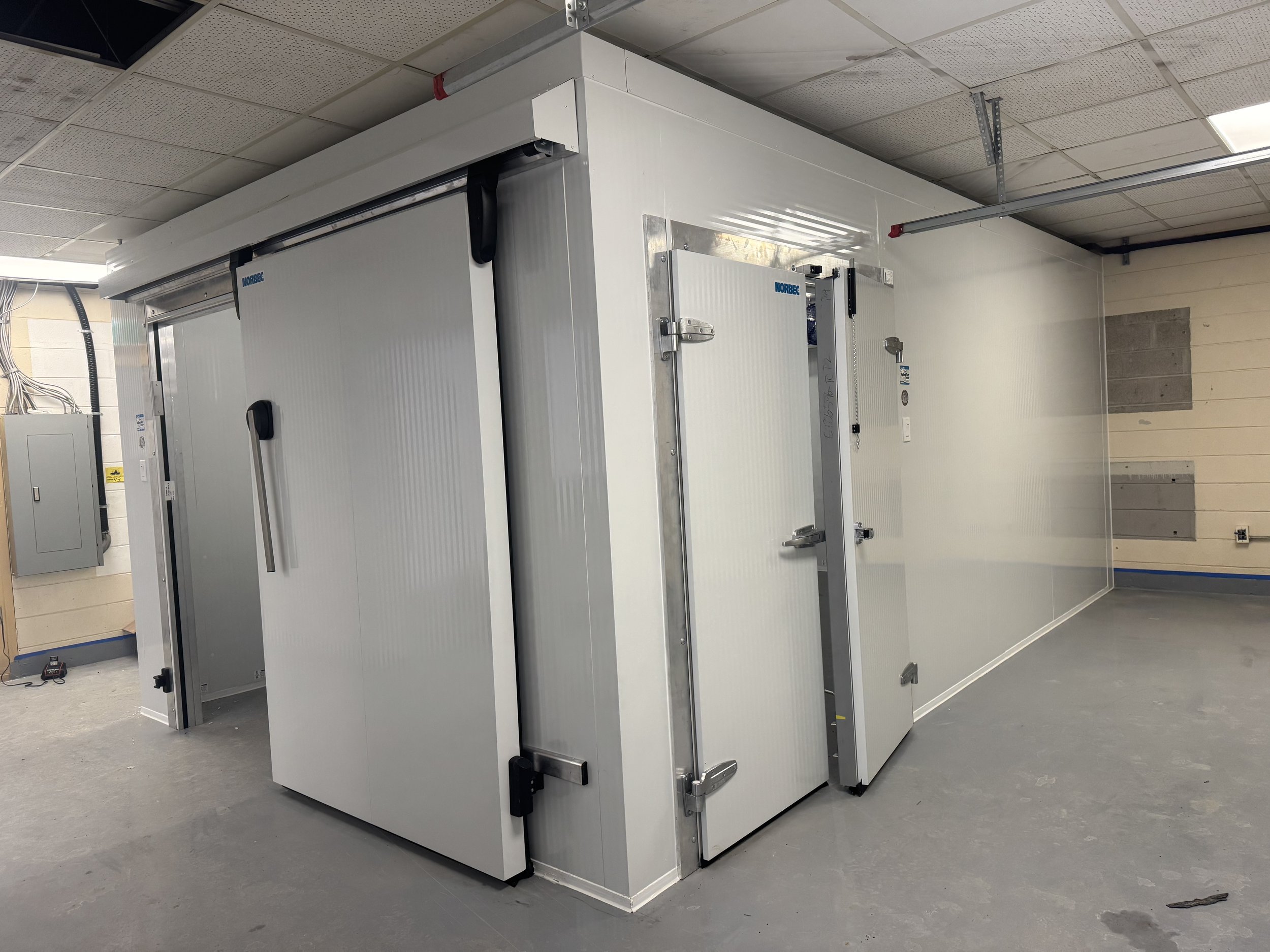 A white walk-in freezer in a cinderblock room.