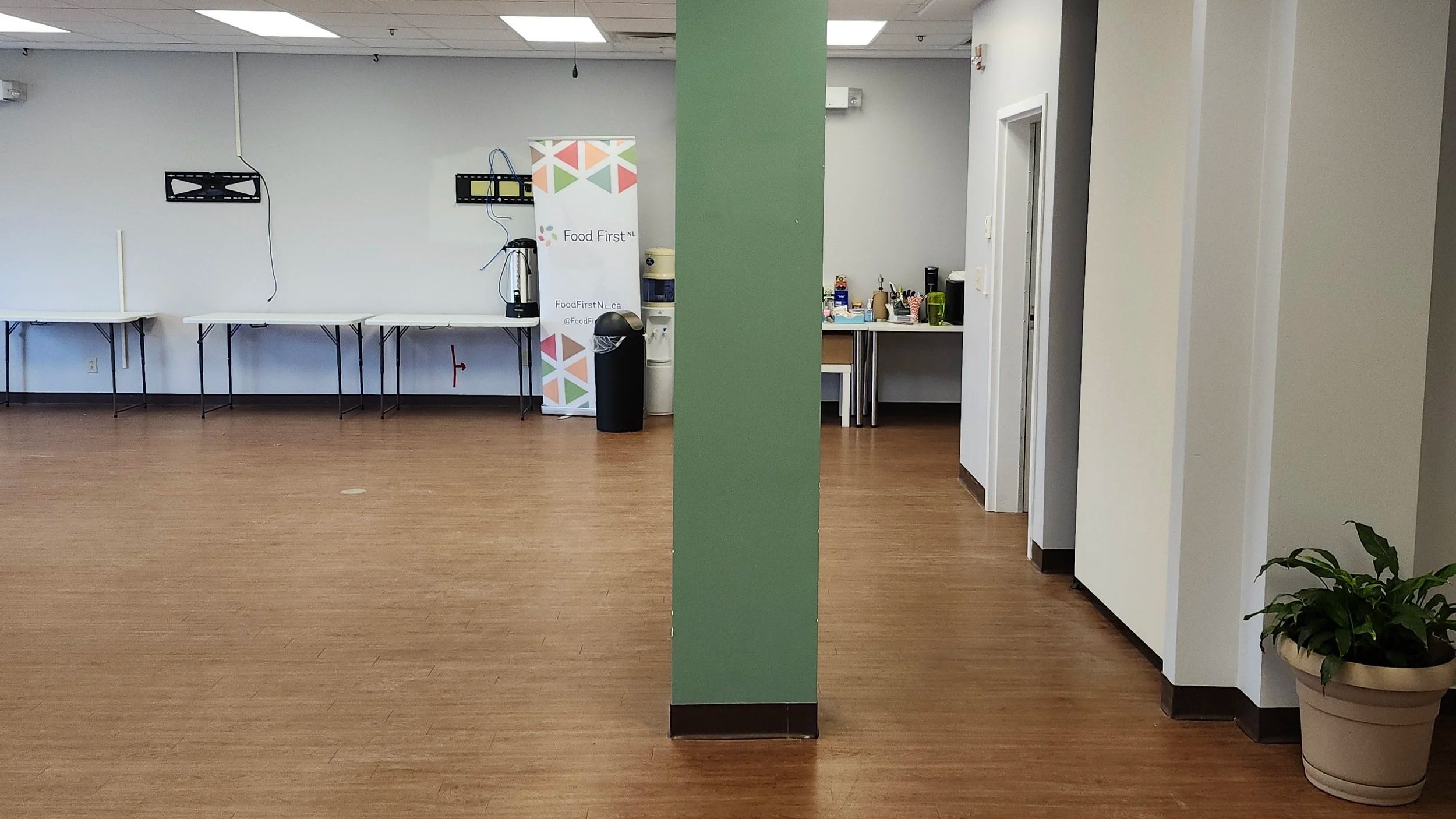 A view of the main room at Our Table pre-renovation, with an empty back wall lined with tables.