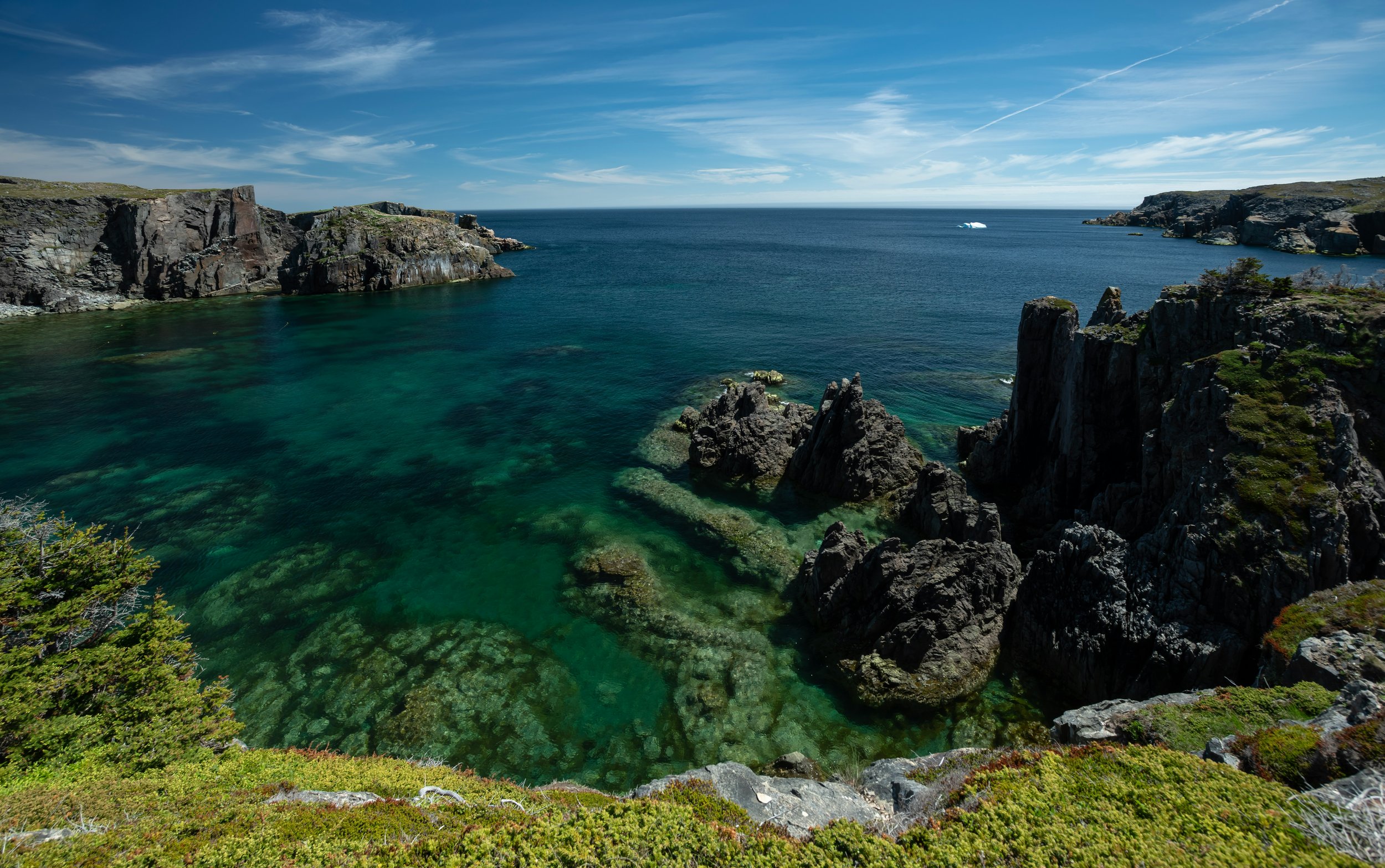 A view of the sea from a rocky cliff on a sunny day.
