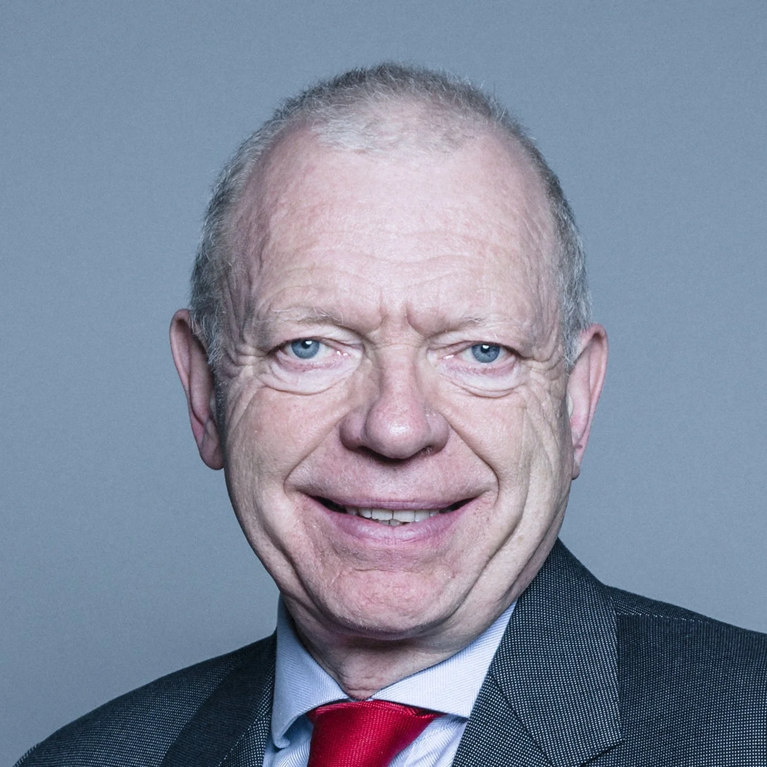Official Portrait of Lord Hunt. He has cropped grey hair and smiles at the camera.