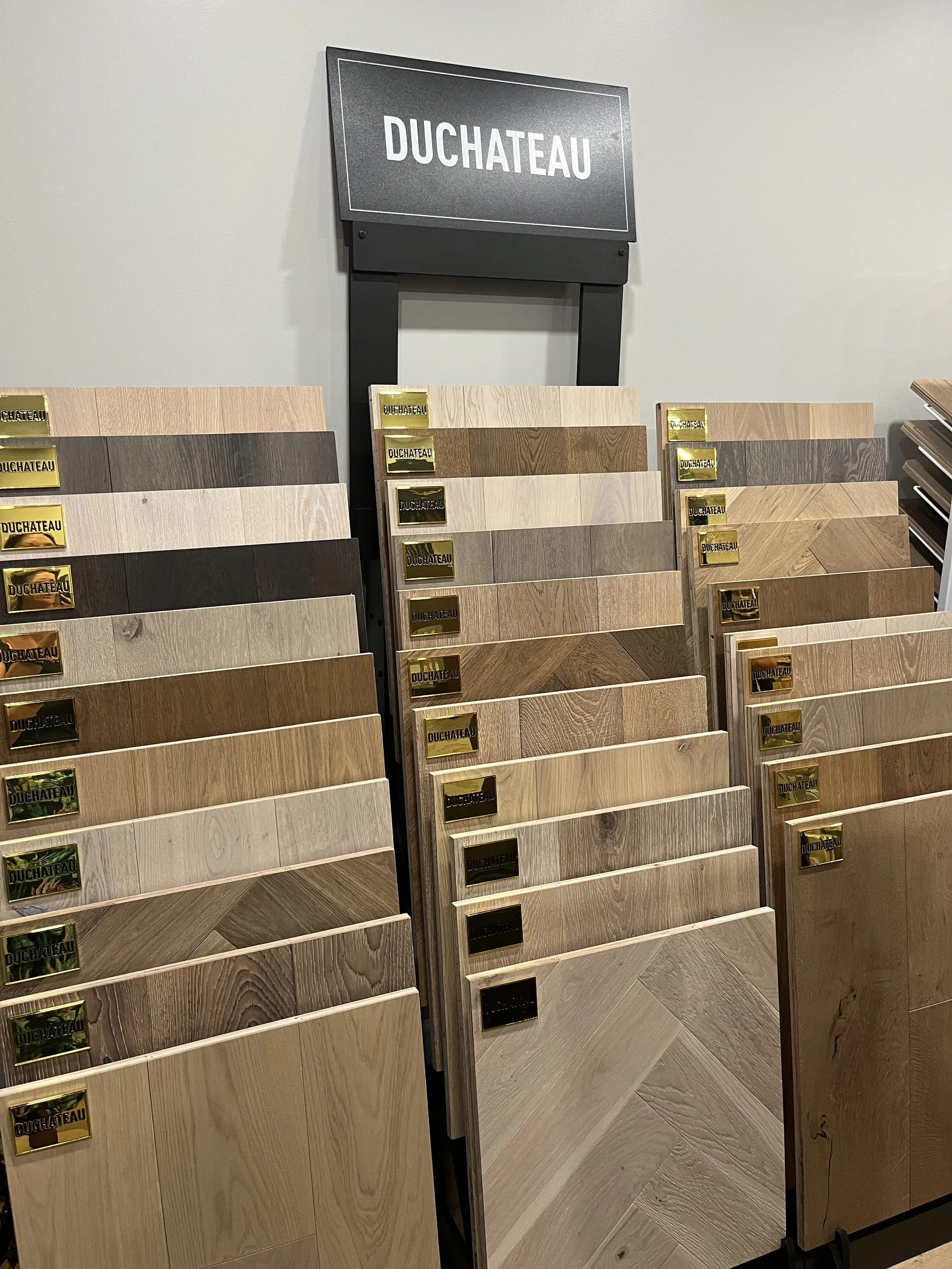 Display of various wood flooring samples with a sign labeled 'DUCHATEAU' above.