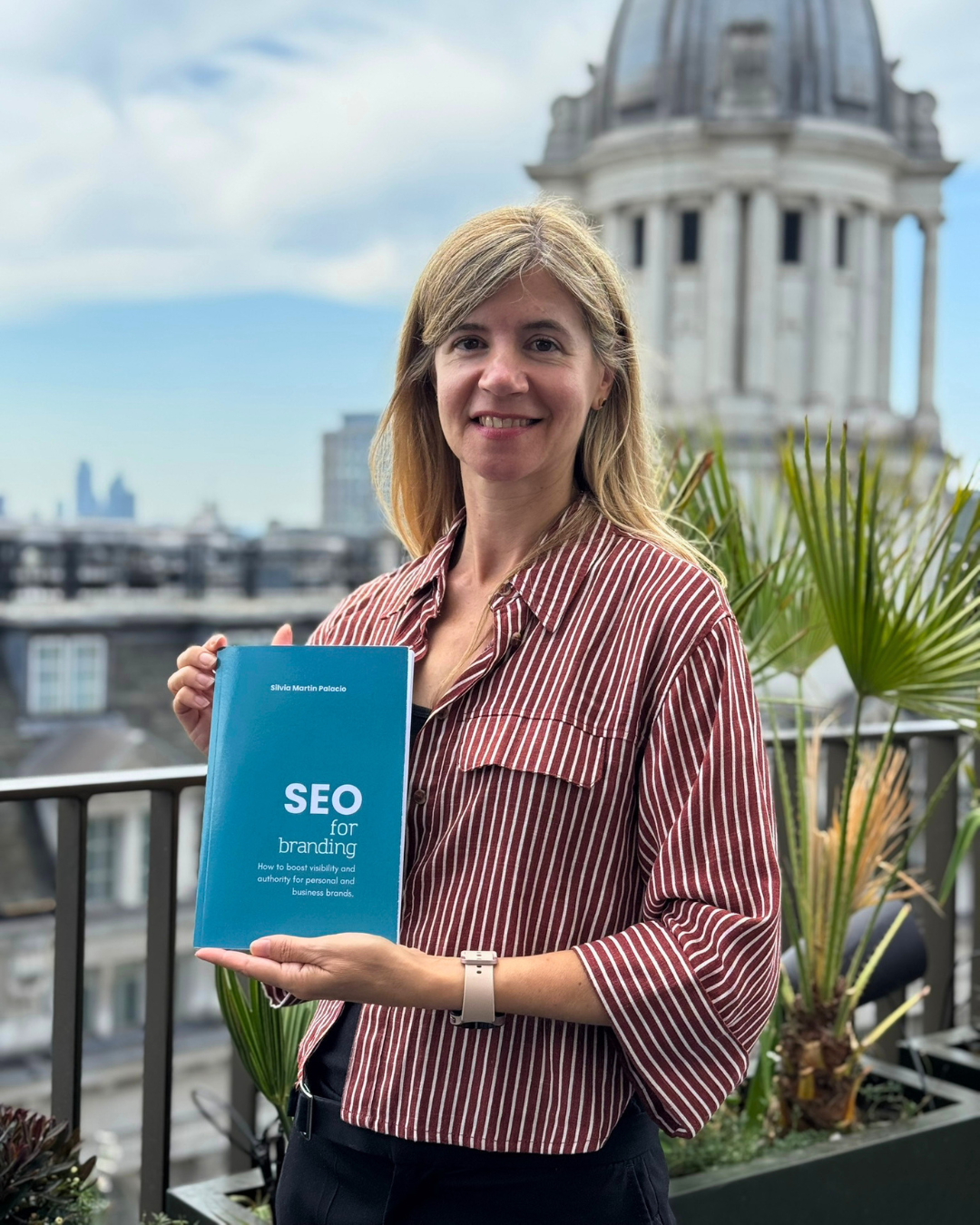 A photo of Silvia Martin holding her book titled SEO for Branding