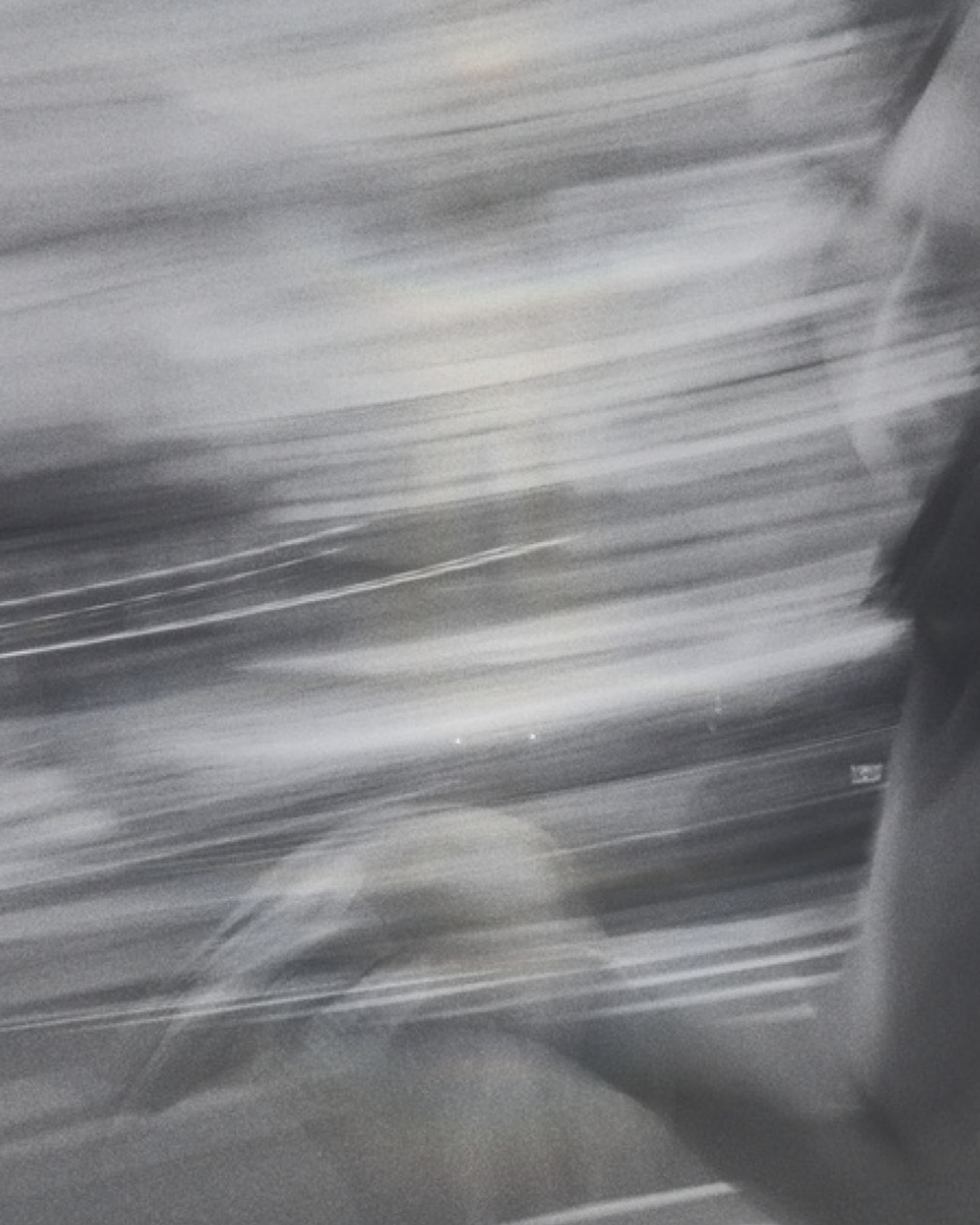 Blurred image of a window with horizontal blinds, possibly inside a vehicle.