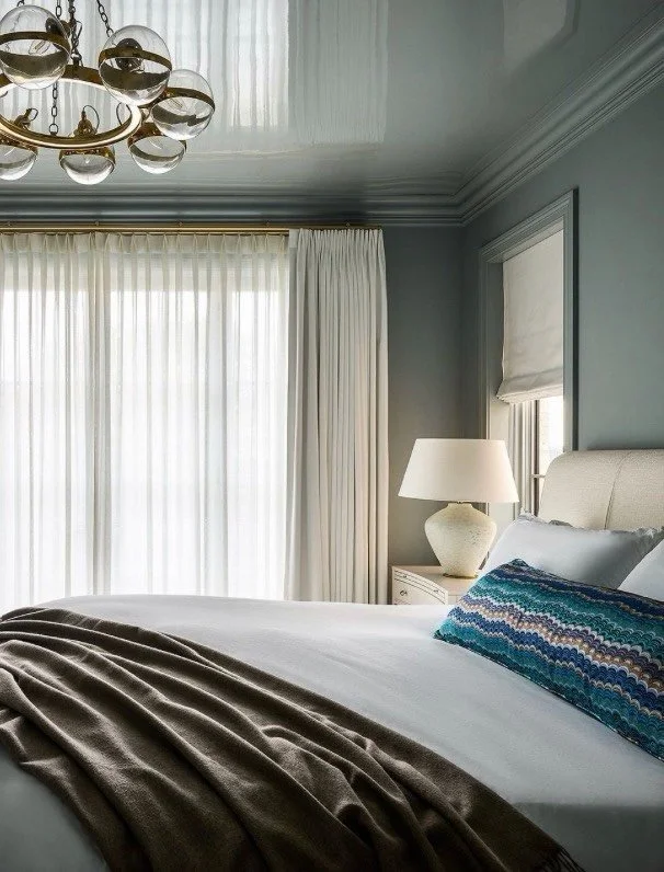 Wrapped in a tranquil, color-drenched wash of soft blue, this Lincoln Park primary bedroom feels both calming and refined. From the walls and detailed molding to the custom built-ins and glossy lacquered ceiling, every surface is enveloped in the sam