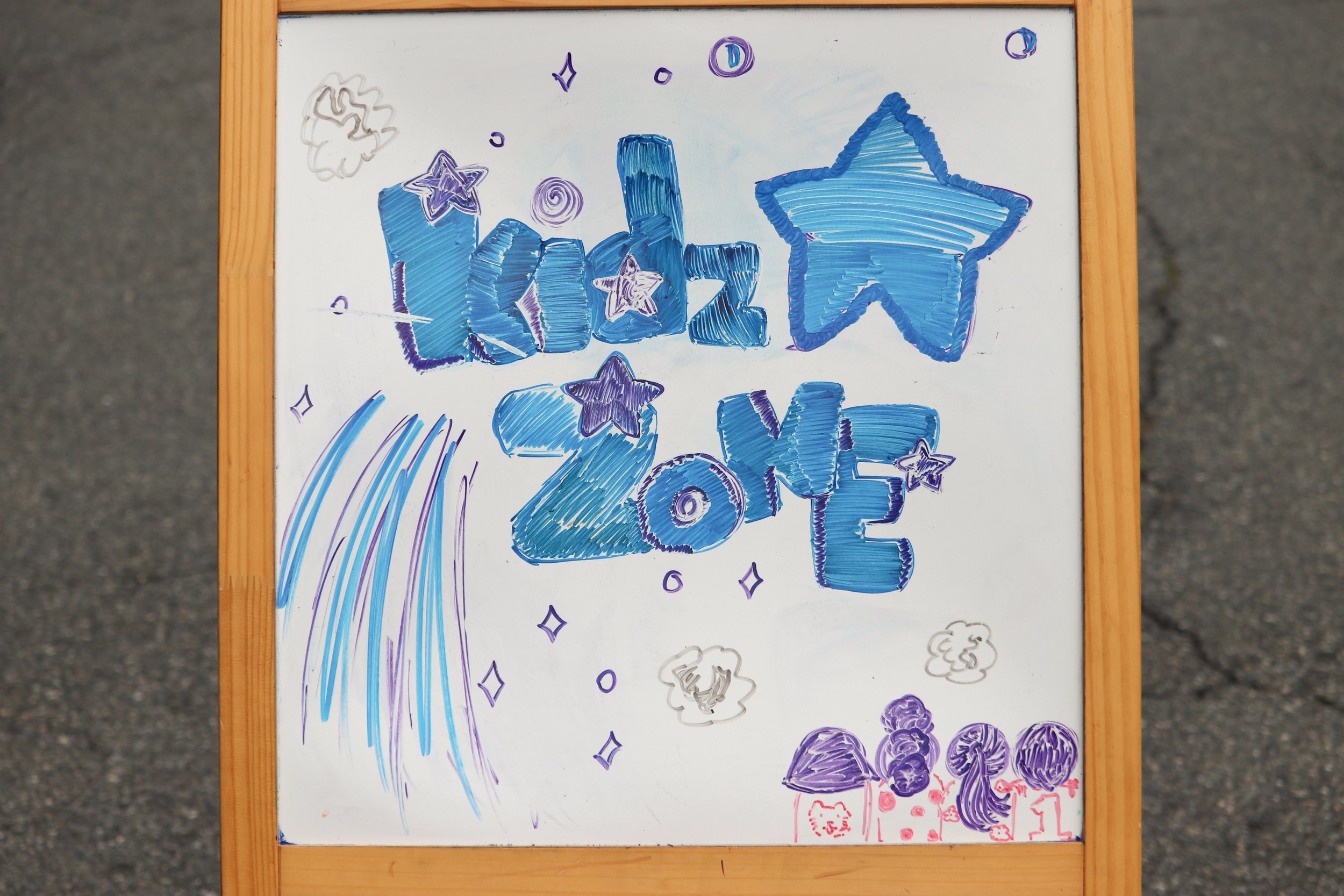 Colorful whiteboard with blue and purple lettering and drawings celebrating the new year. The words "Hello 2023" are written in large, stylized letters, with a star and other decorative elements around. There are also rainbow-like lines and small cha