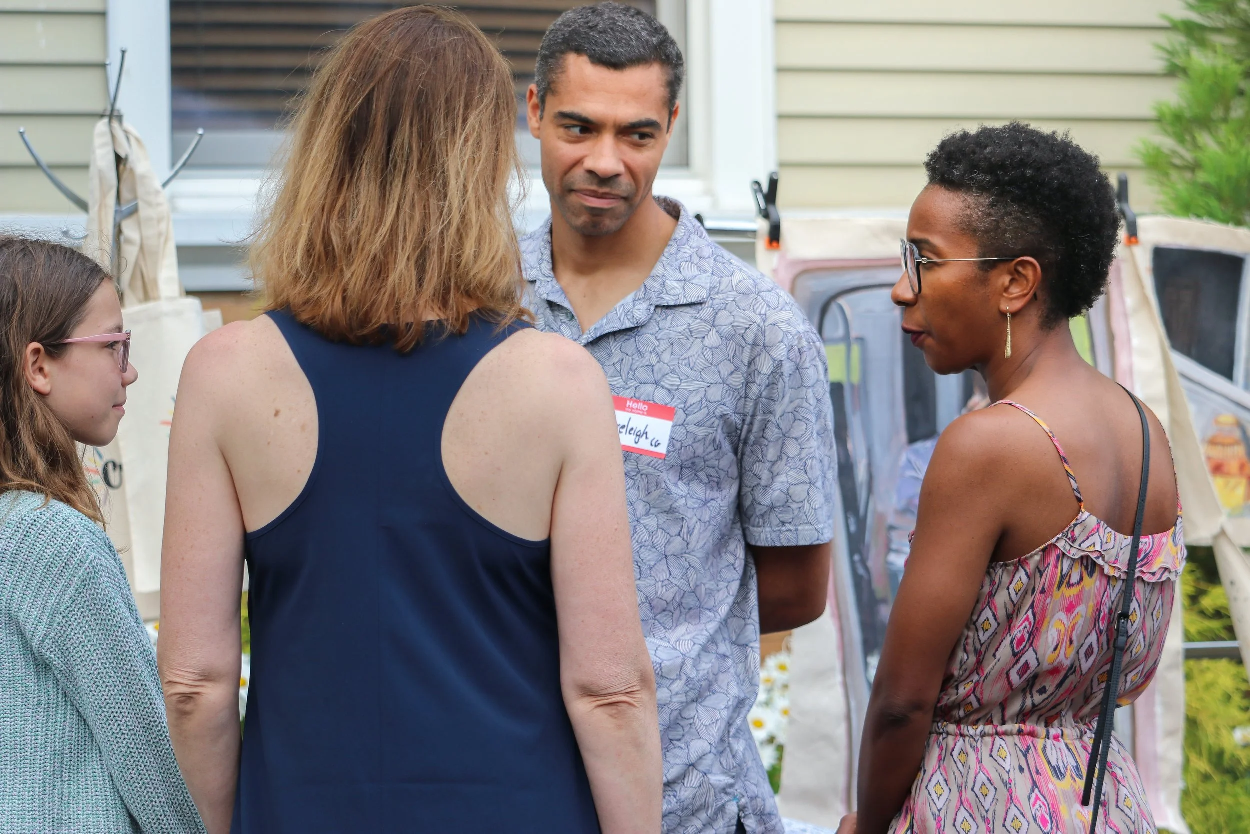 Four people standing outside, engaged in conversation at a social gathering, community.