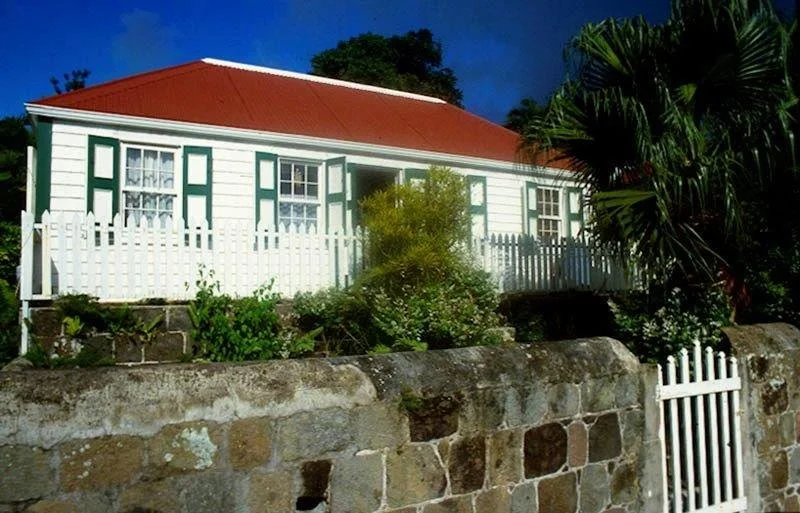 clapboard cottage with a red tin roof