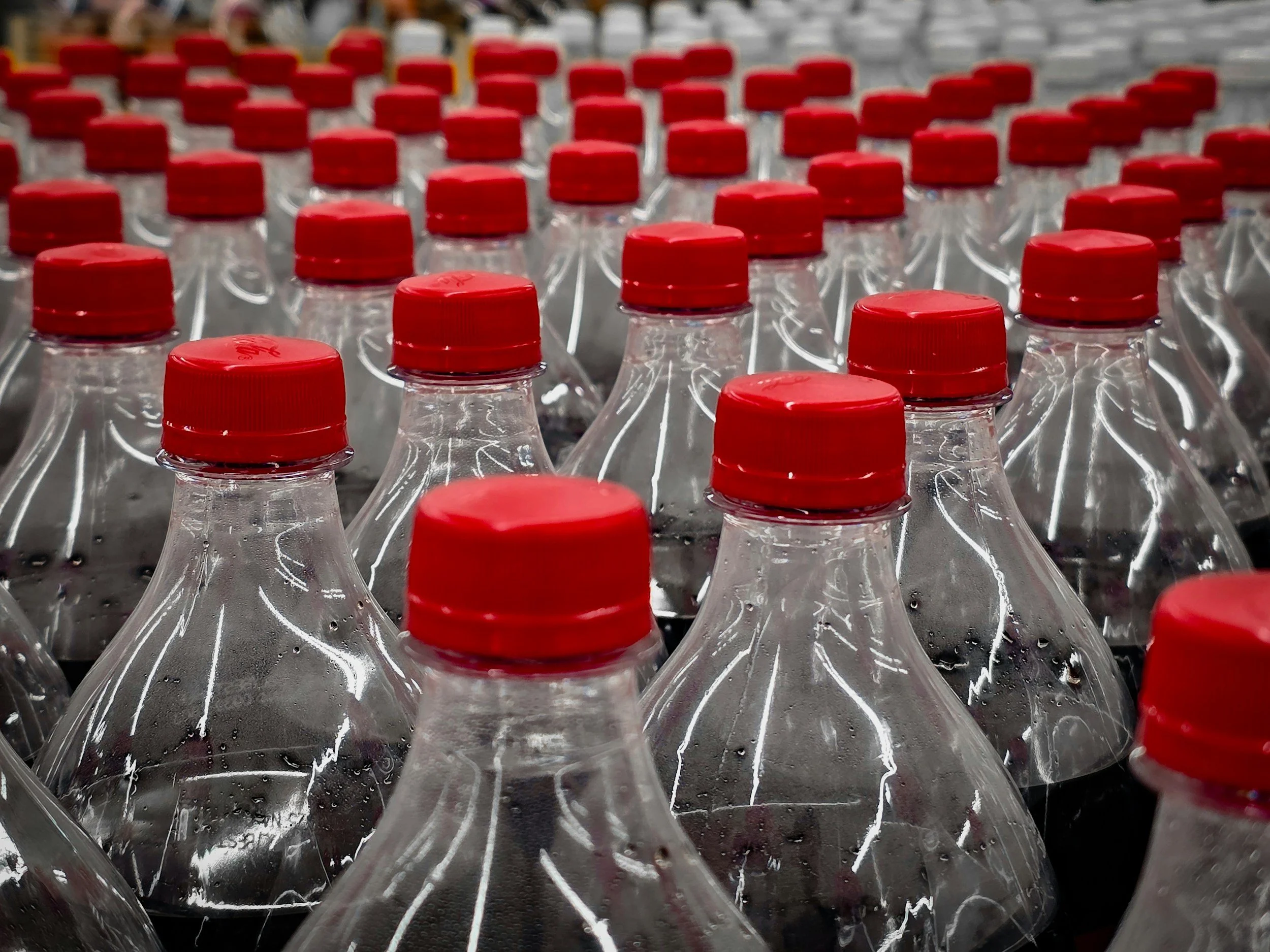 Close up of the necks and tops of soft drinks bottles