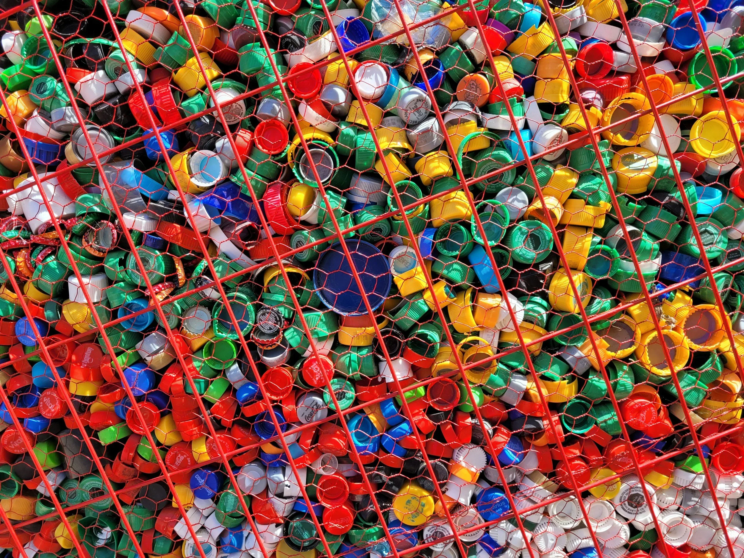 Plastic bottle tops in a red metal cage