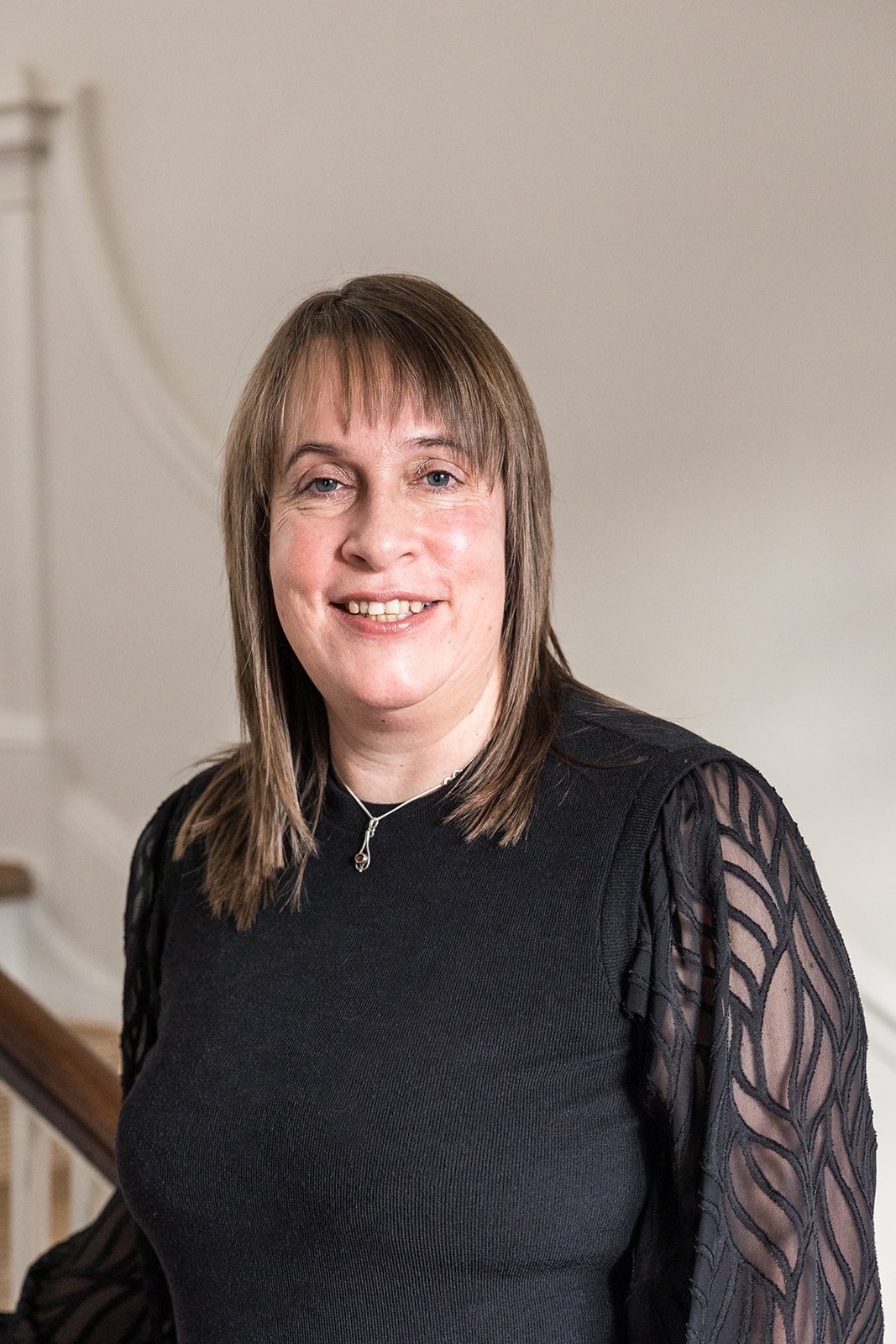 A lady smiling with brown hair and a black jumper