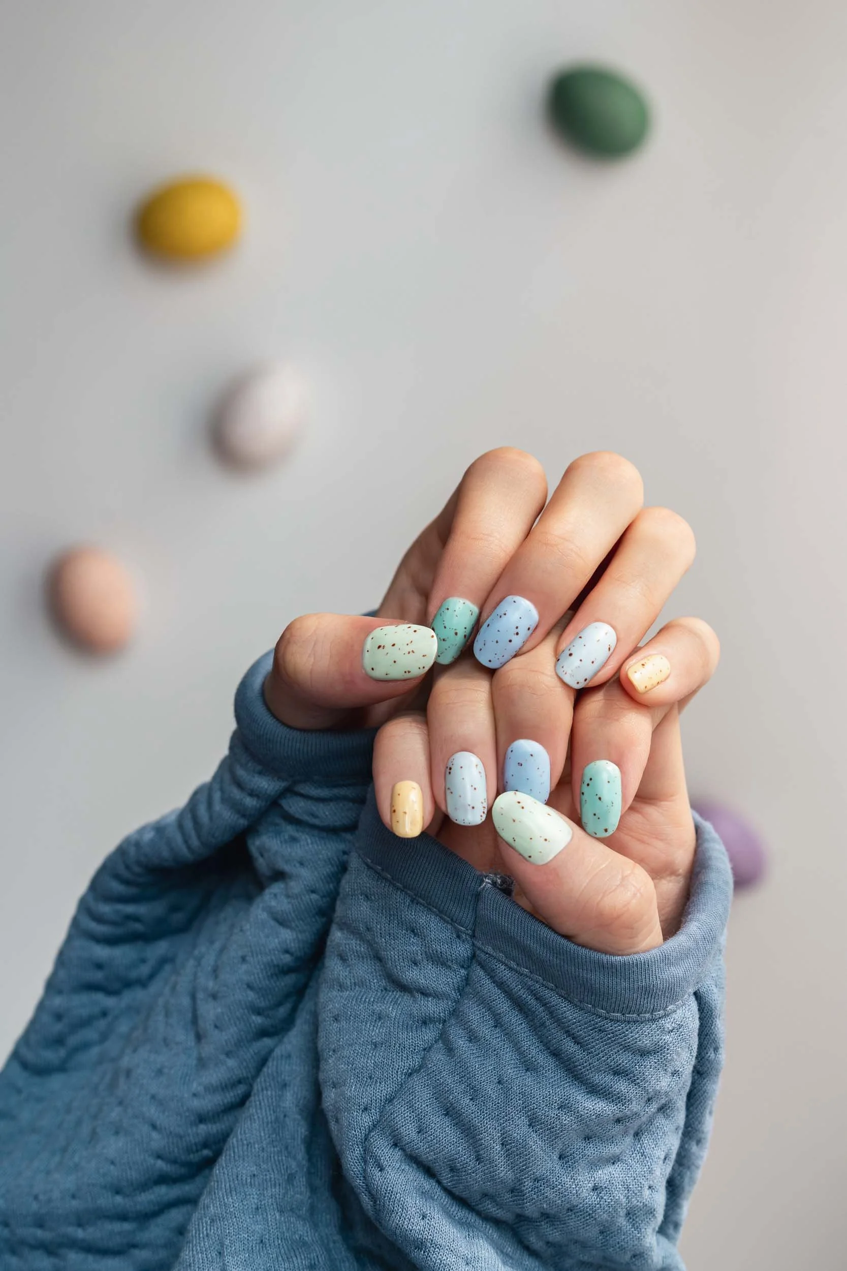 A Becoming Carmen spring manicure featuring a speckled chocolate egg nail design with matte pastel colours and brown freckles.