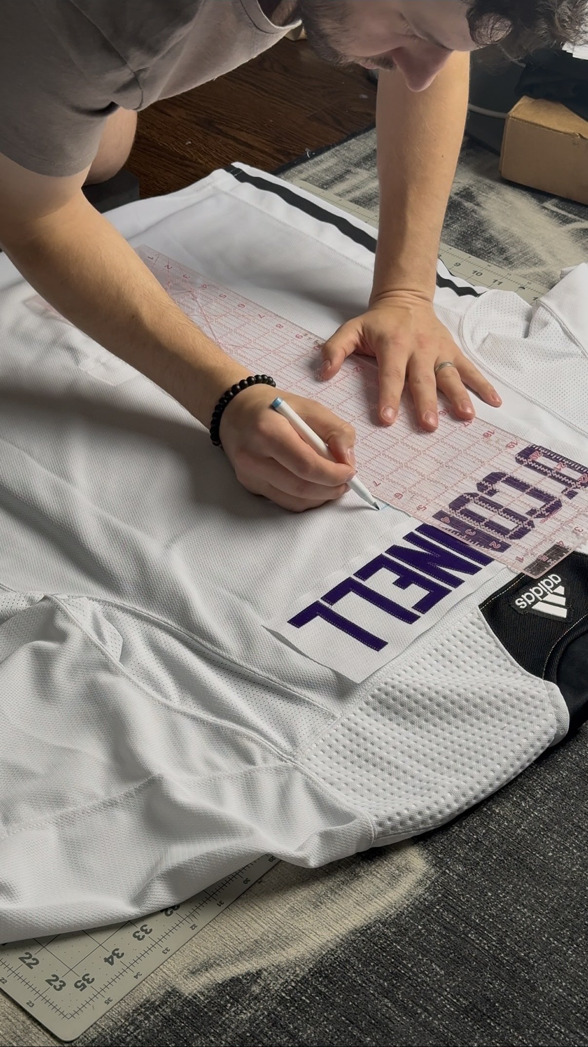 Custom wedding jersey nameplate being manually positioned before sewing