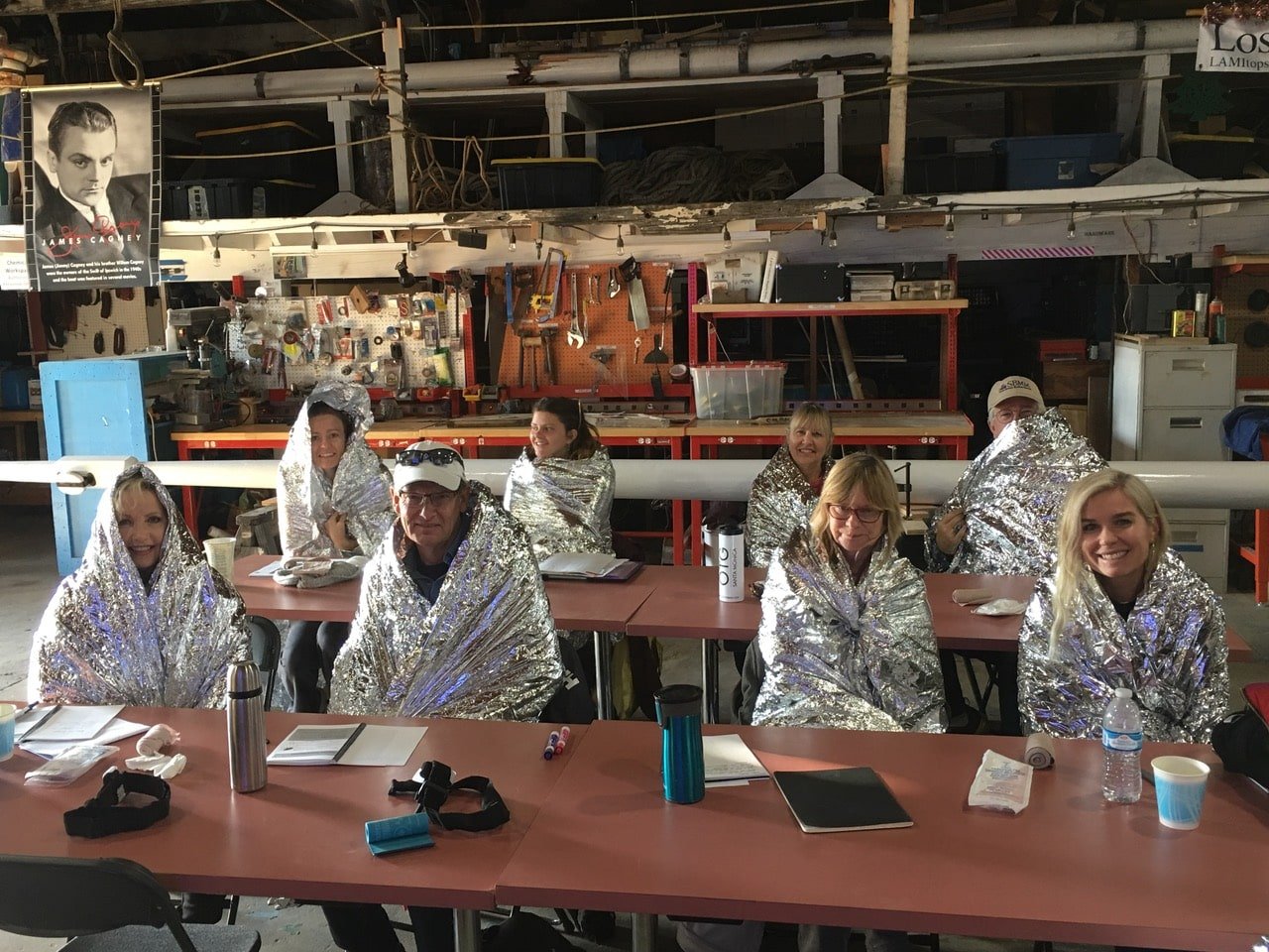   A group of trainees modeling emergency blankets while learning warming techniques for at sea.  