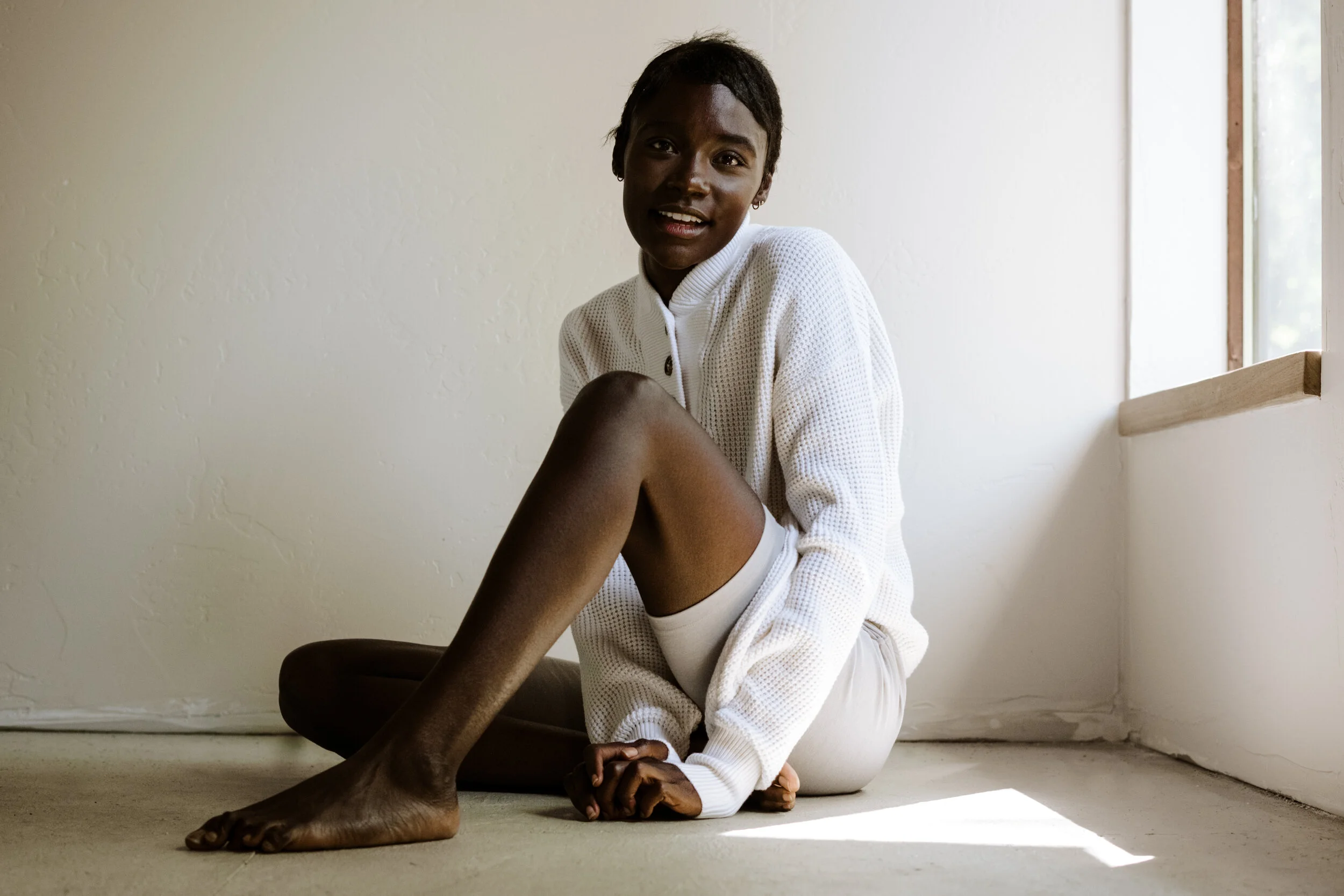 Woman wearing Lunya loungewear in a softly lit bedroom