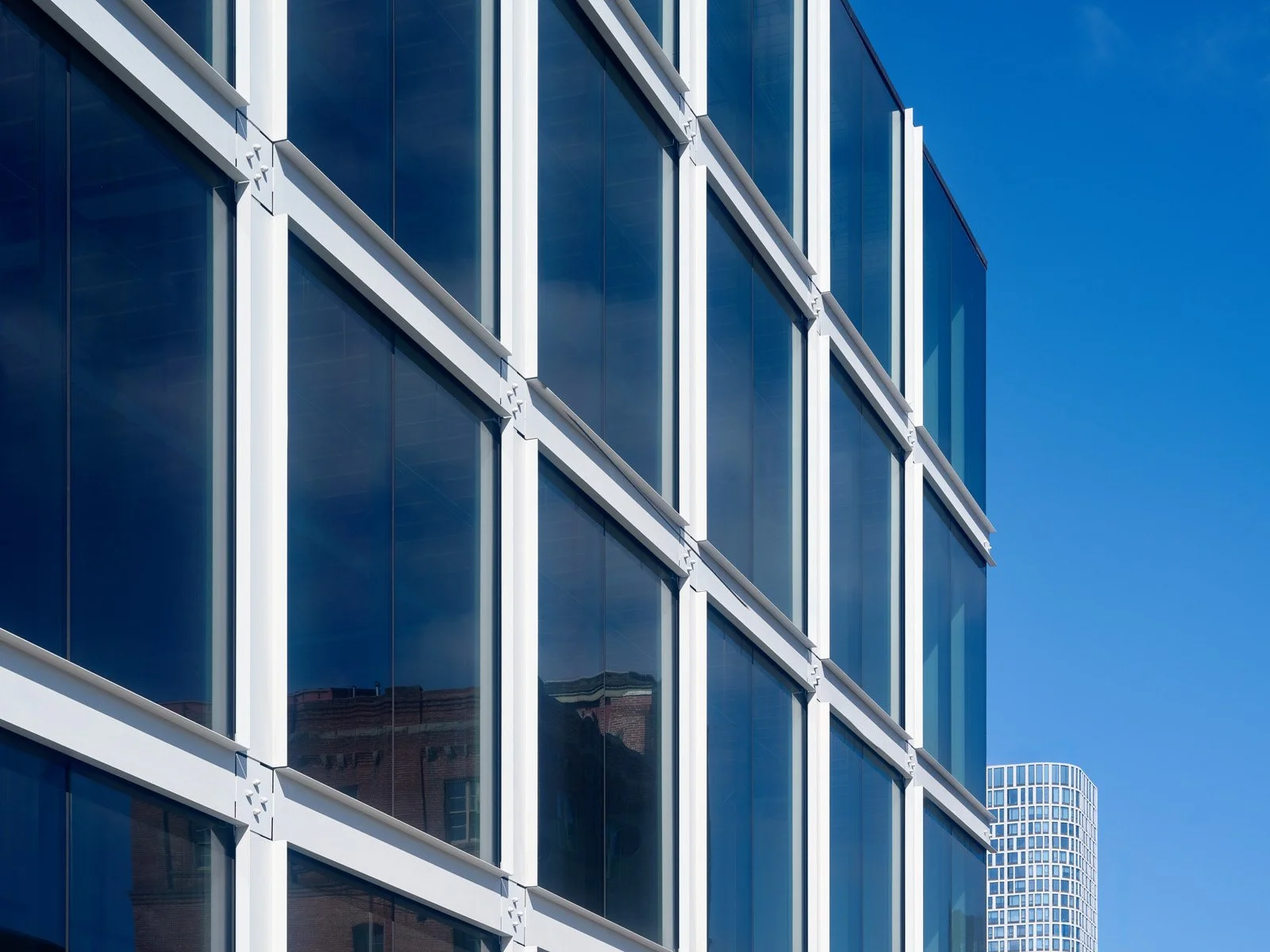 Close-up view of modern glass building with reflective windows against clear blue sky.