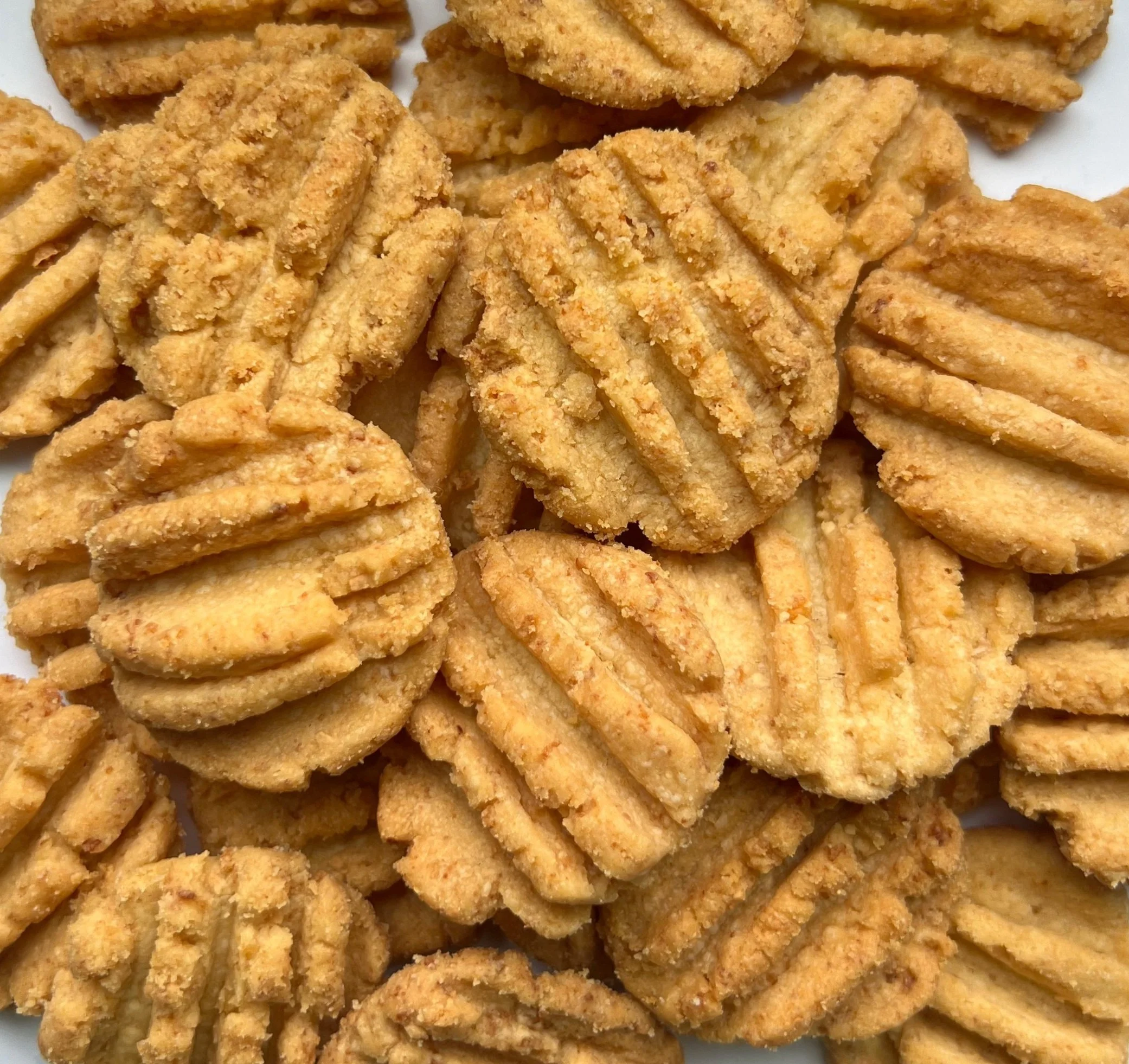 Close-up of several textured almond cookies with ridges and crumbly surfaces.