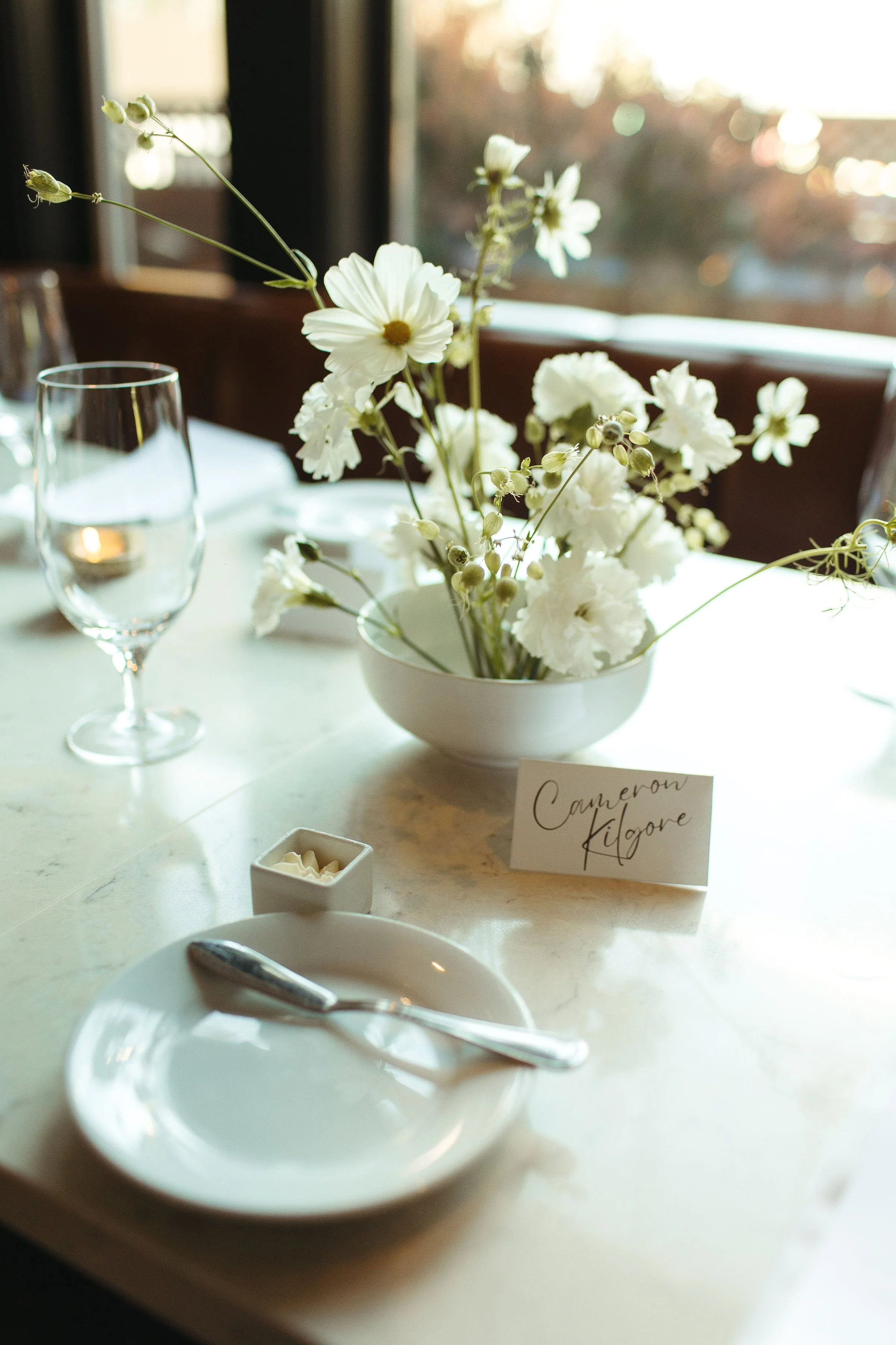 A table setting with a floral centerpiece of white flowers in a white bowl at Ariana Restaurant in Bend, Oregon