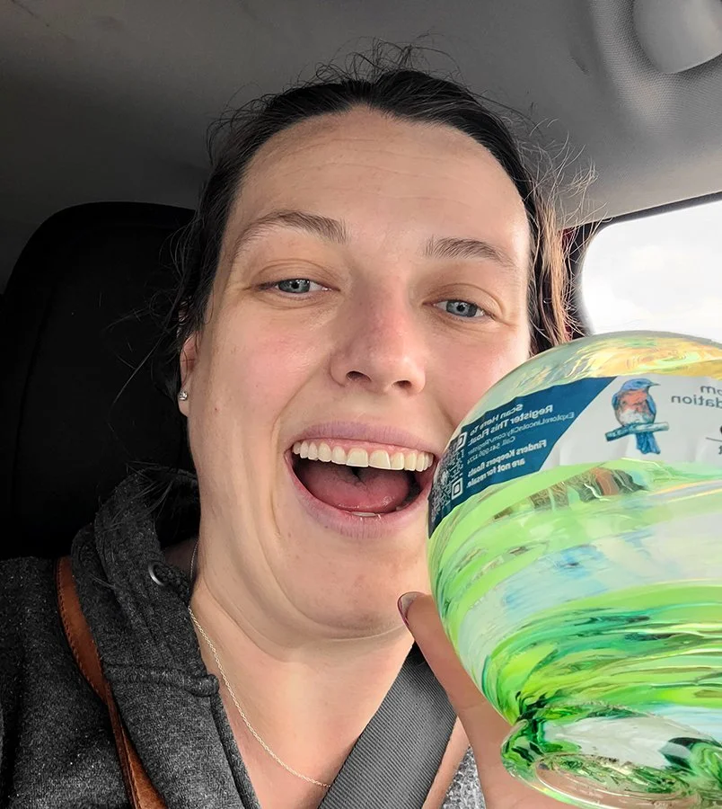 woman in her car holding up her glass float