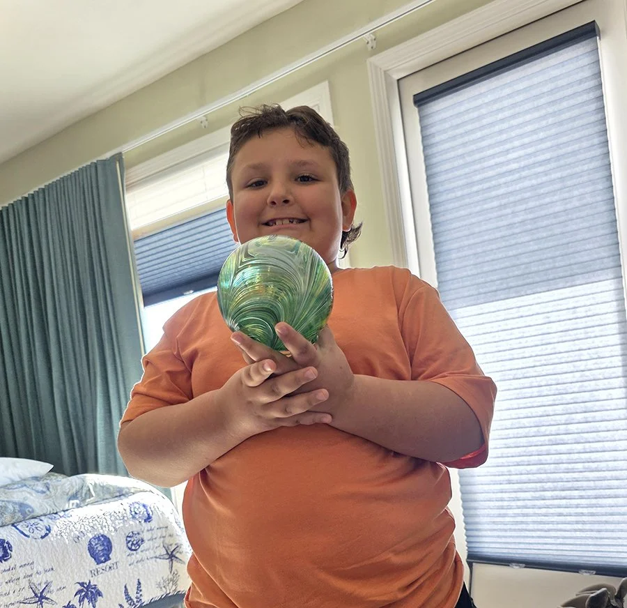 young kid proudly holding his glass float