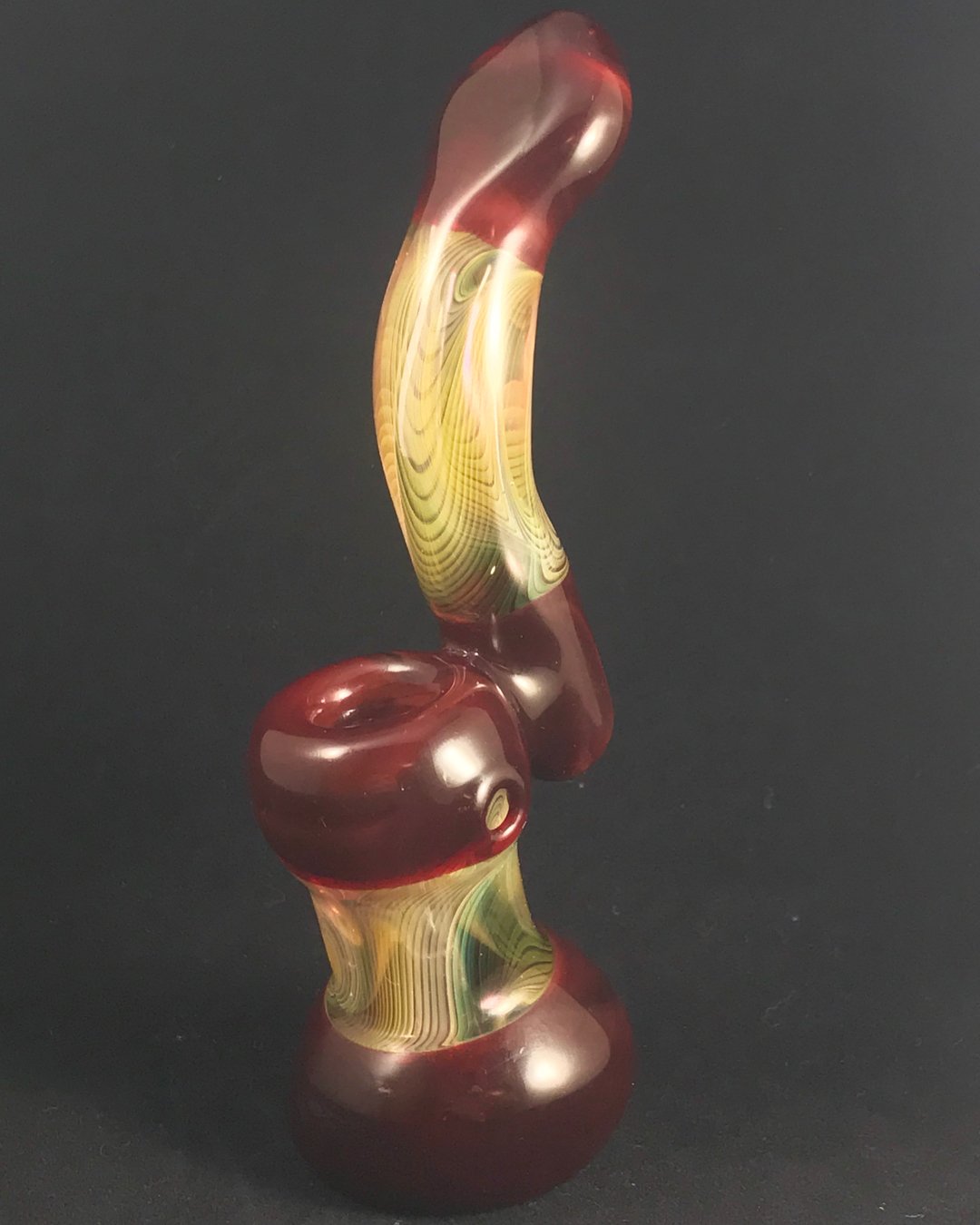 Colorful glass art sculpture with swirls of red, yellow, and green on a black background.