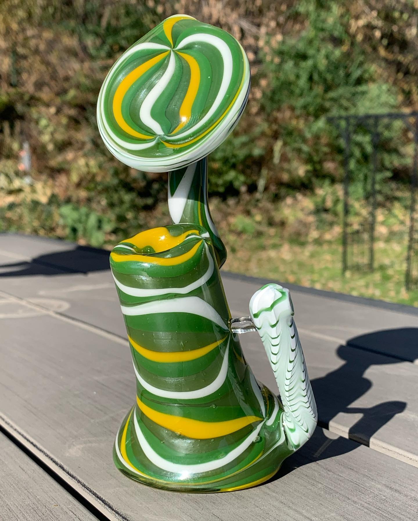 Colorful glass art sculpture with swirls of green, white, and yellow, resembling a snail