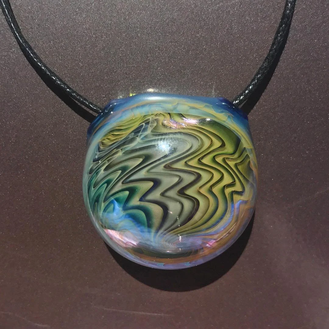 Colorful glass pendant with swirling pattern on a black cord.